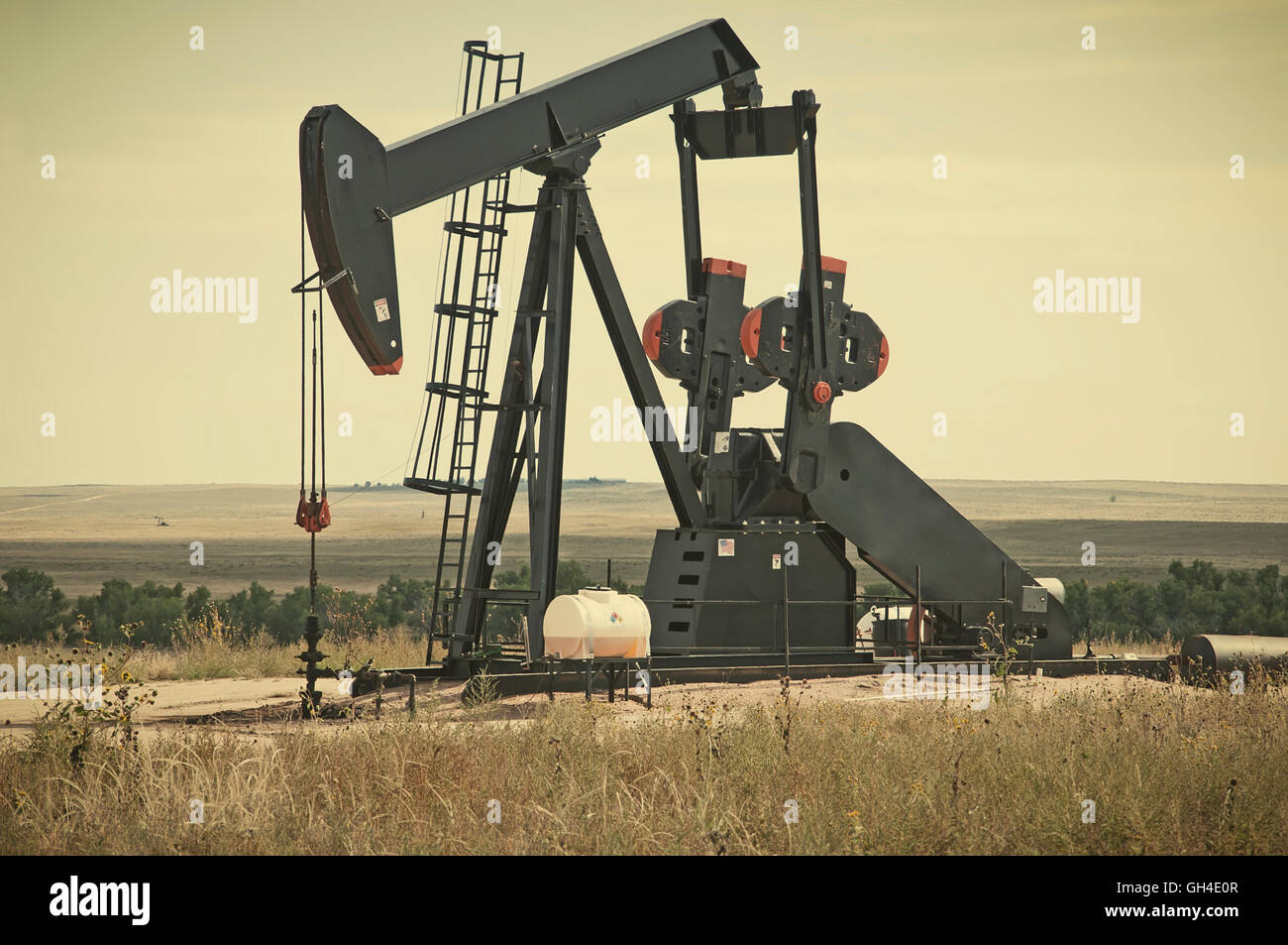 Working pump jack pulling crude oil out of an oil well in Colorado, USA. Retro instagram look. Stock Photo