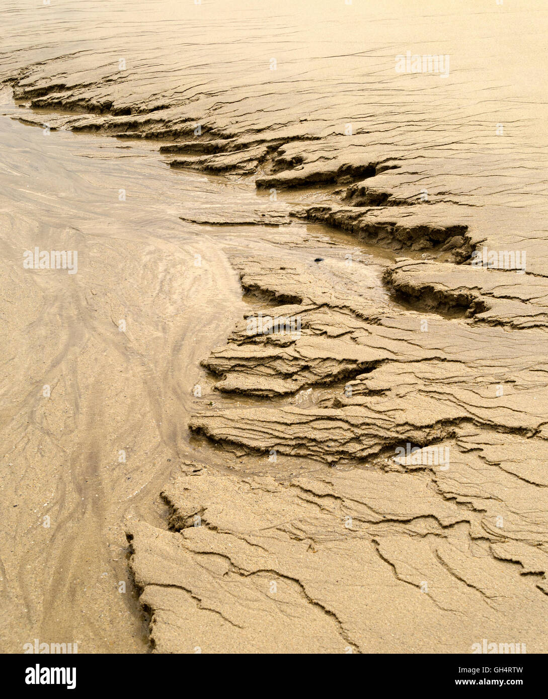 Patterns in yellow beach sand caused by water erosion Stock Photo