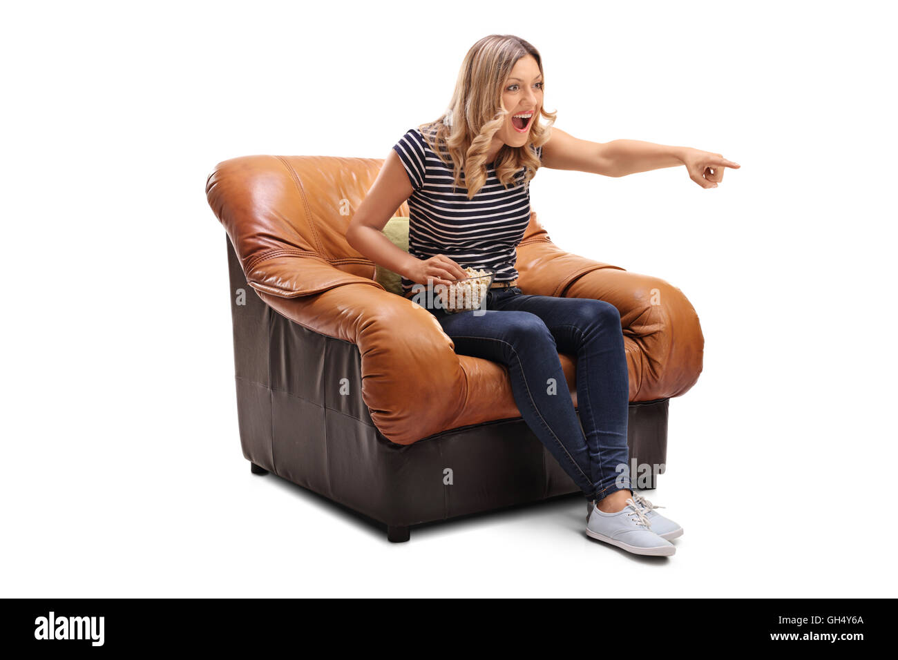 Laughing young woman watching something hilarious on TV and having some popcorn isolated on white background Stock Photo