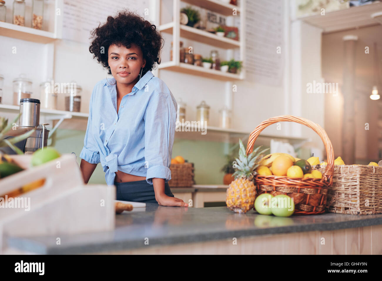 Portrait of confident young woman standing at counter in juice bar looking at camera. African female juice bar owner. Stock Photo