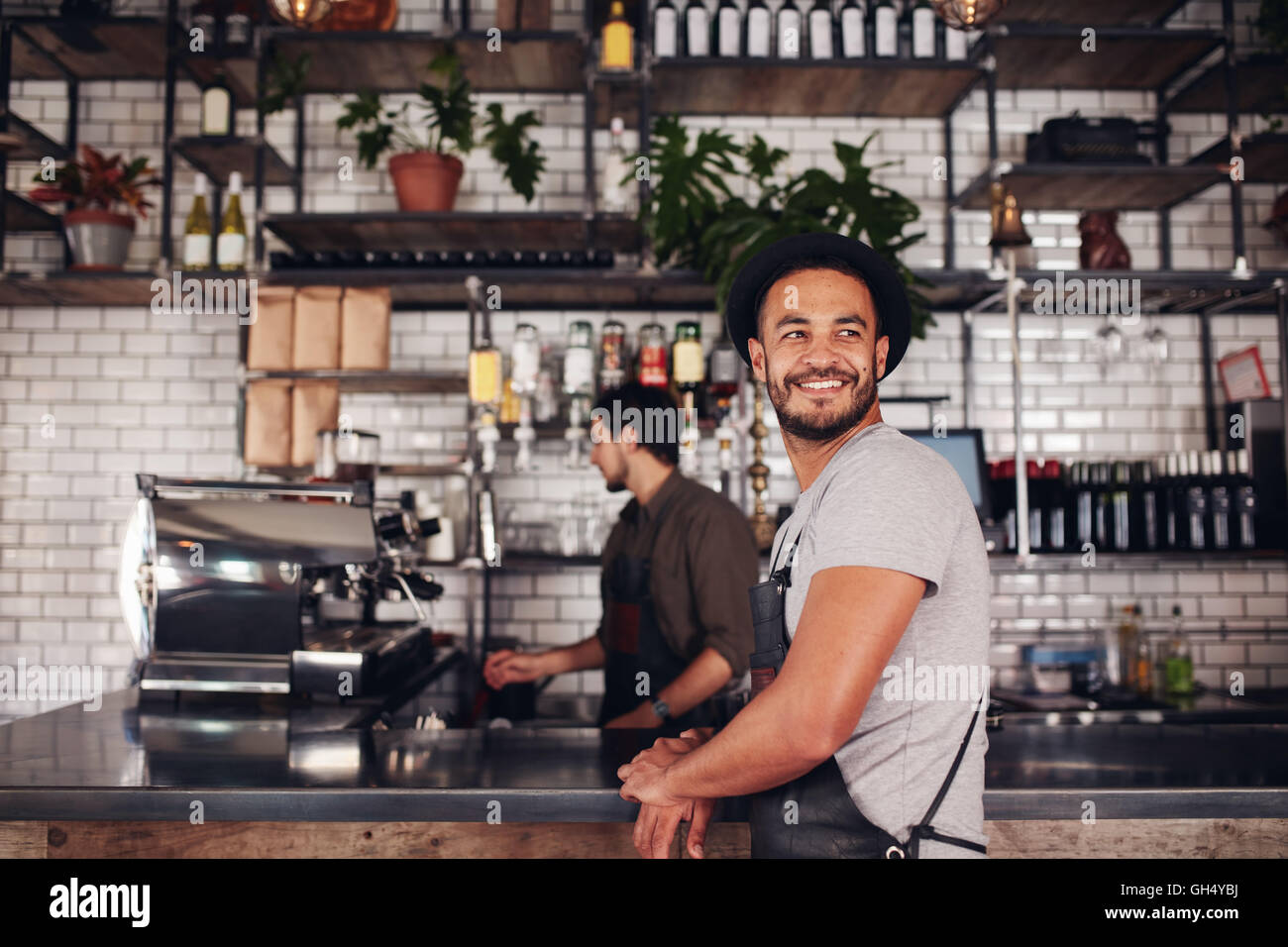 Coffee shop owner standing with barista working behind the counter