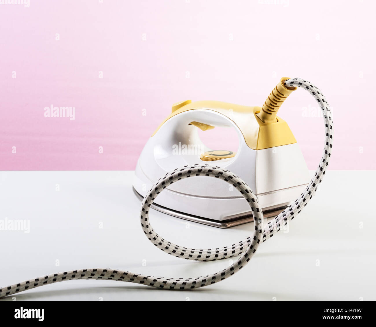 Yellow steam smoothing iron on pink background. Single object with clipping path Stock Photo