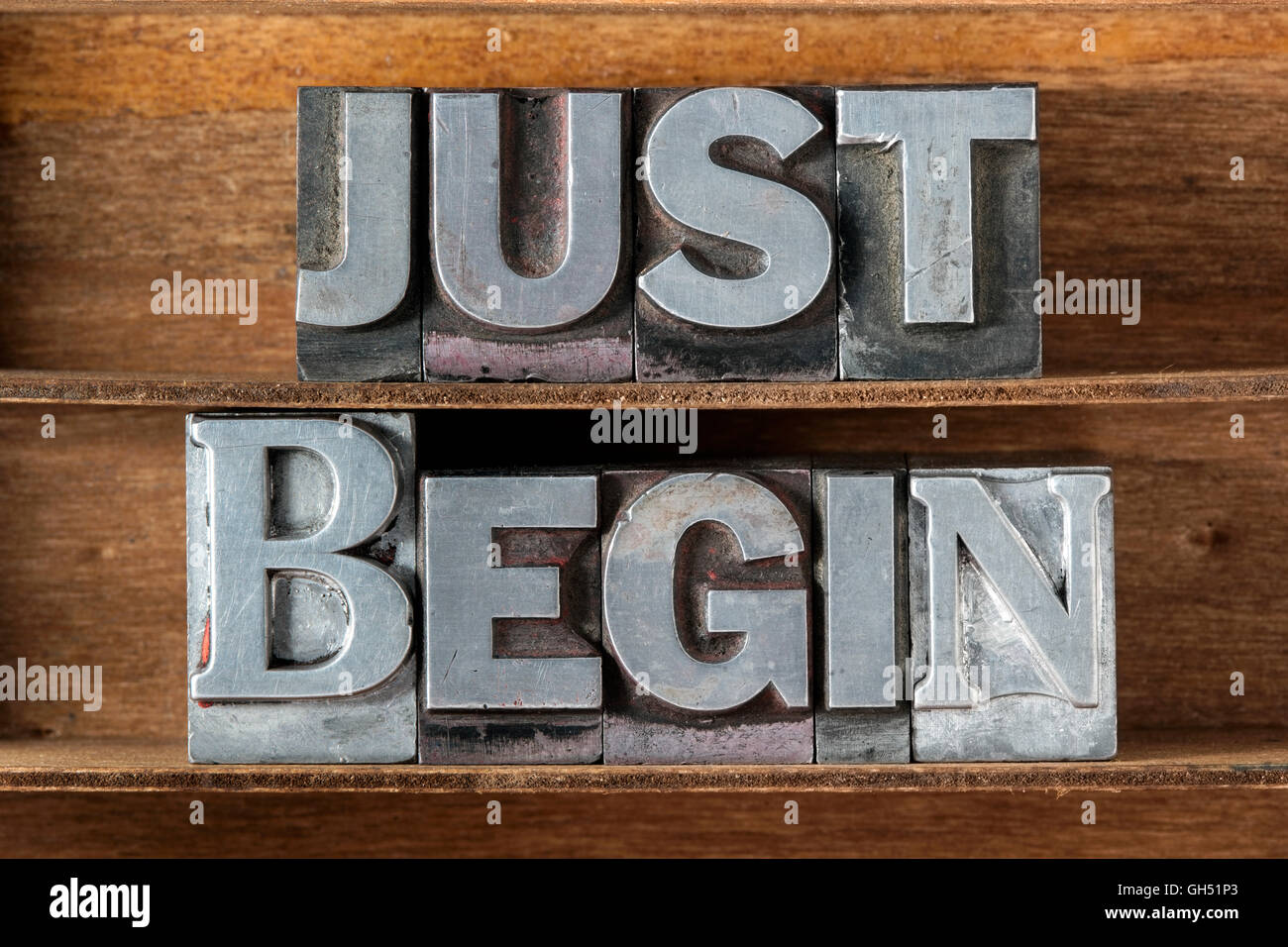 just begin phrase made from metallic letterpress type on wooden tray Stock Photo