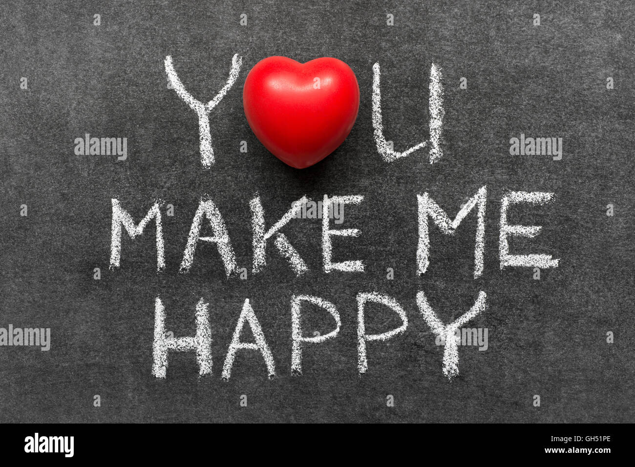 you make me happy phrase handwritten on blackboard with heart symbol instead of O Stock Photo