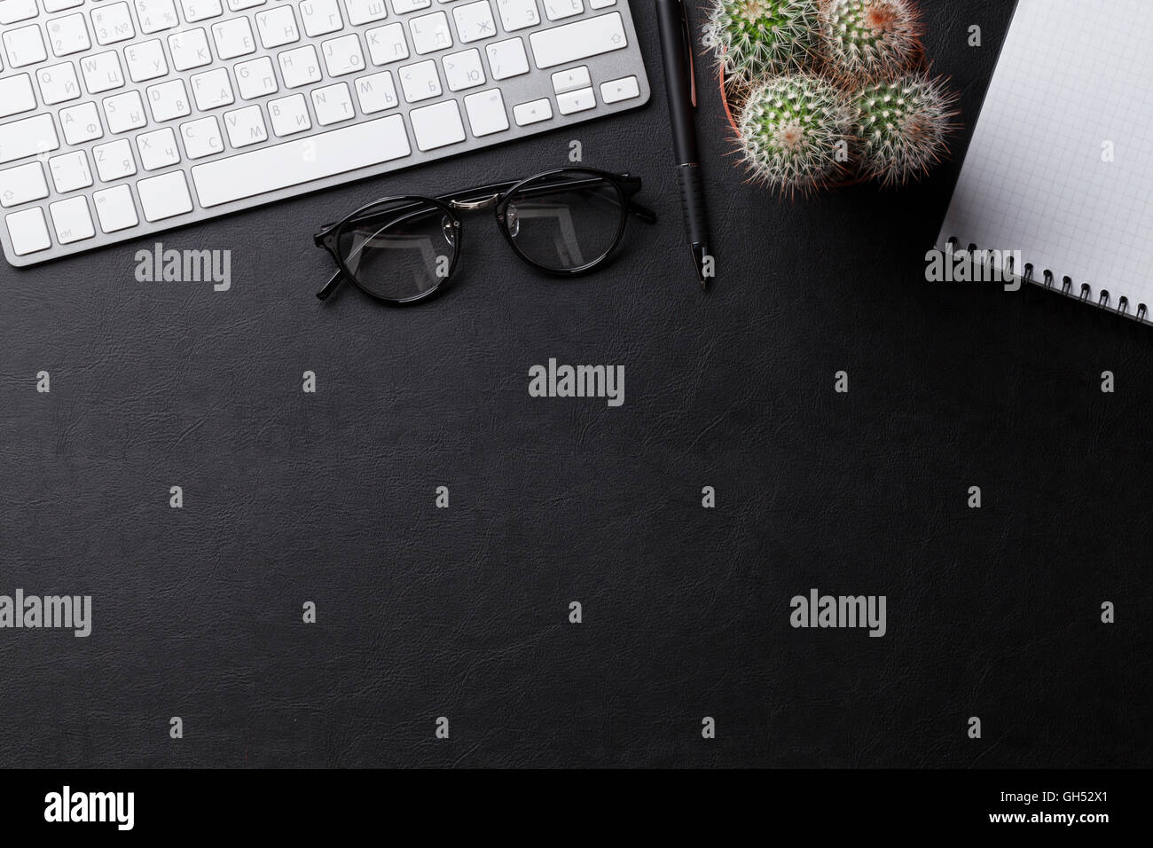 Office desk with pc, notepad and cactus over leather texture. Top view with copy space Stock