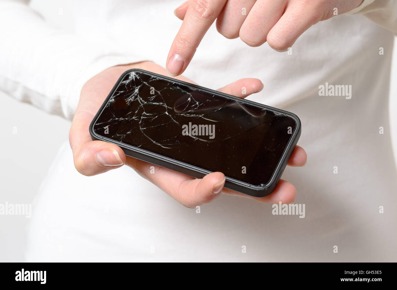 Close up of one woman in white blouse holding broken mobile phone in her hands Stock Photo