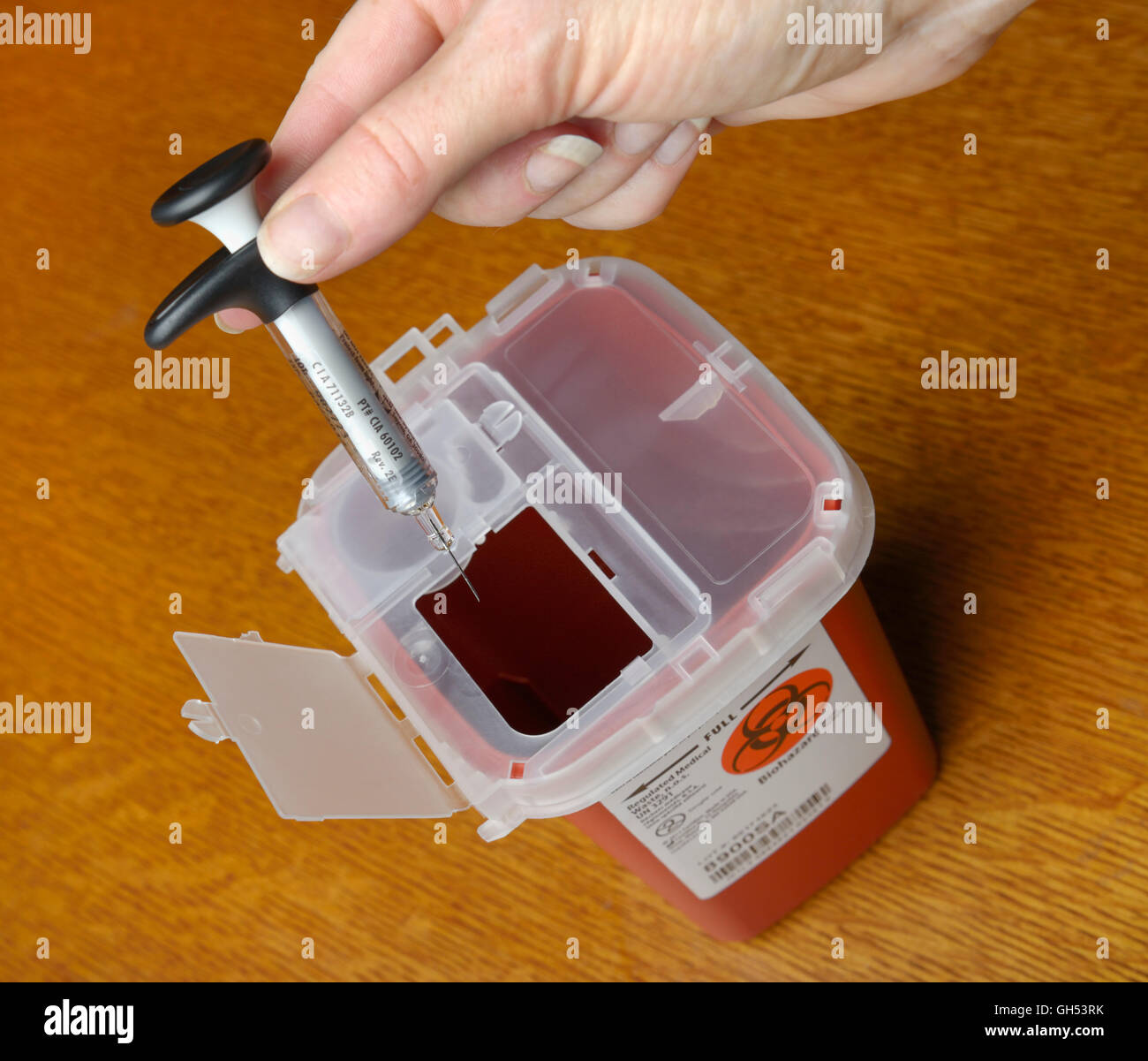 Disposing of a syringe in a sharps container for medical waste after an injection of medicine Stock Photo