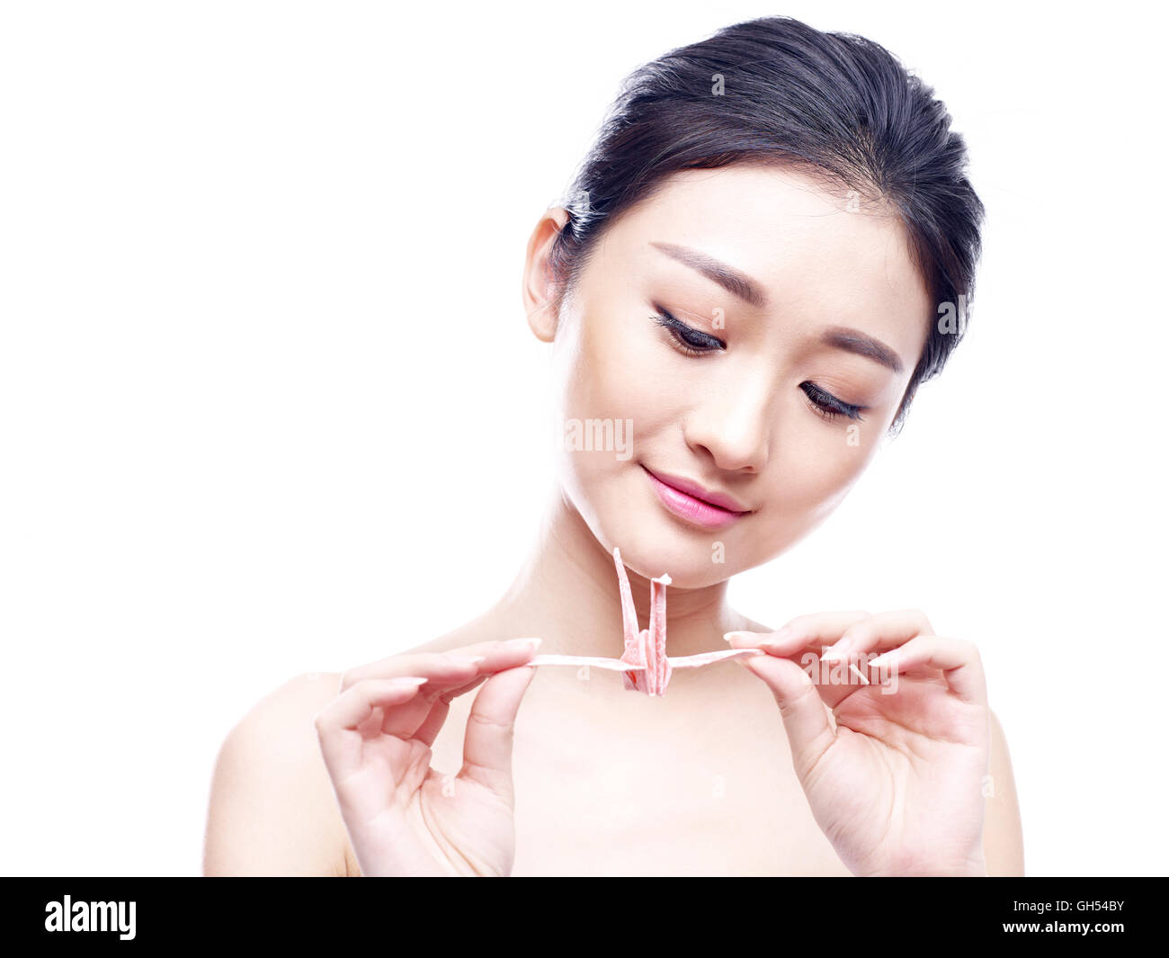 young asian woman holding and looking at a paper crane, isolated on white background. Stock Photo