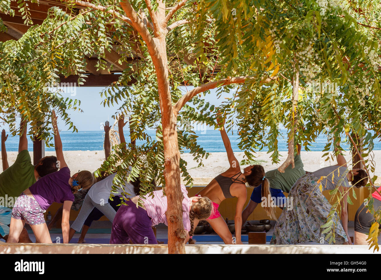 A group of people doing a class of yoga near the beach Stock Photo