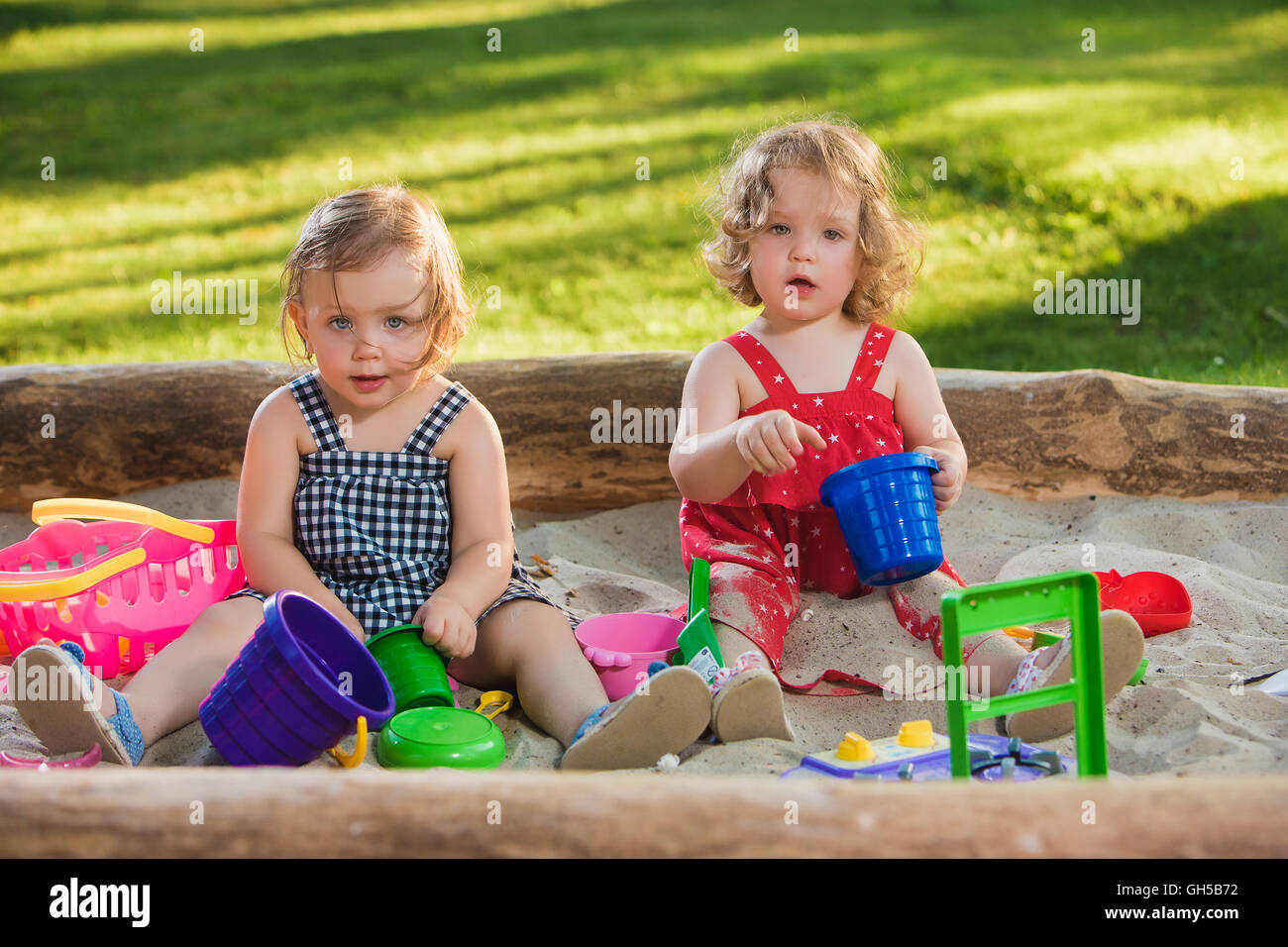 The two little baby girls playing toys in sand Stock Photo - Alamy
