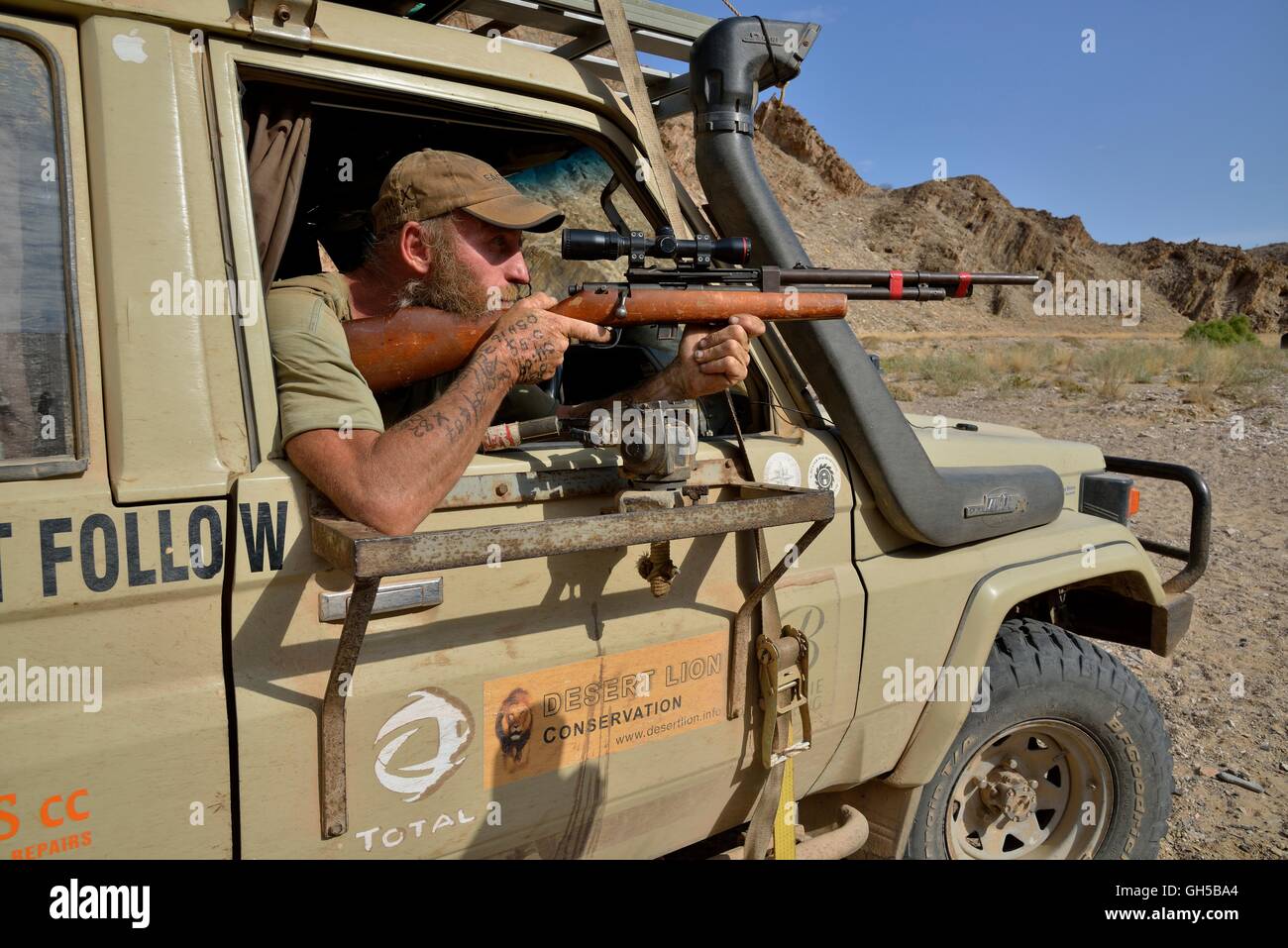 geography / travel, Namibia, lion researcher Dr. Flip Standert with rifle in his research vehicle in the Obias riverbed, of a lateral branch of the Hoanib, Kaokoveld, Additional-Rights-Clearance-Info-Not-Available Stock Photo