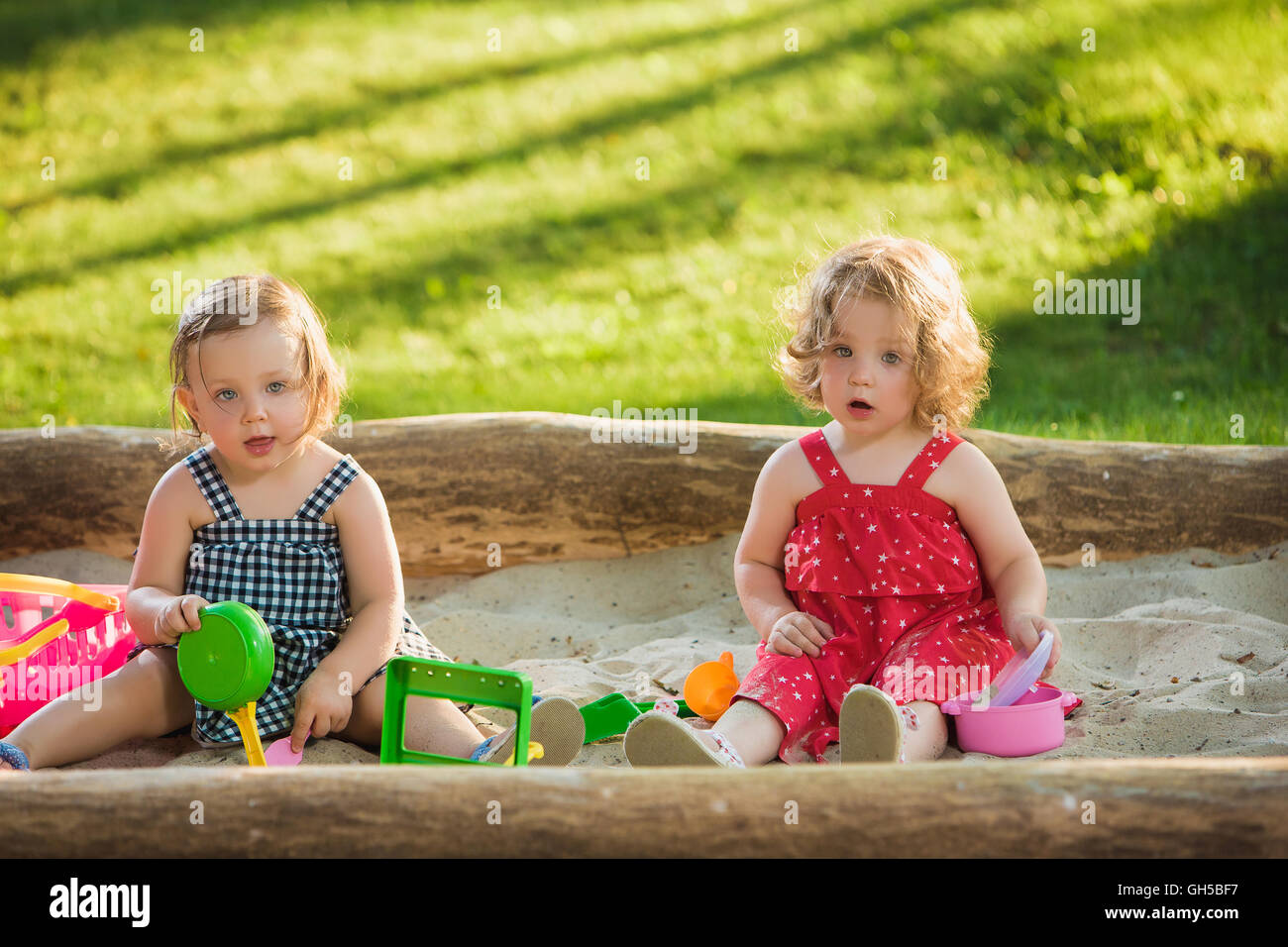 The two little baby girls playing toys in sand Stock Photo - Alamy