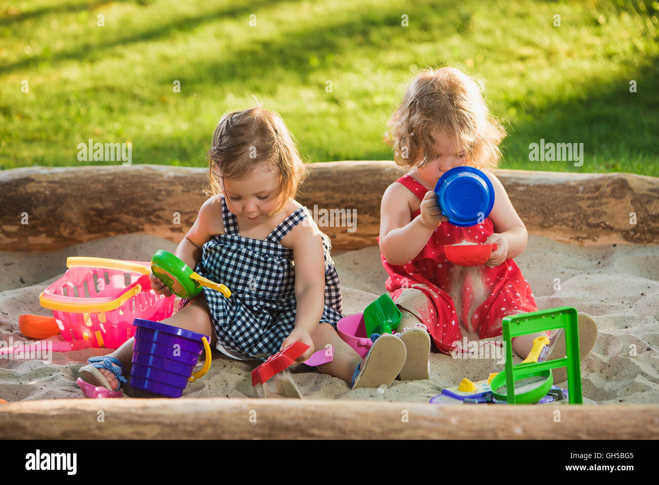 The two little baby girls playing toys in sand Stock Photo - Alamy
