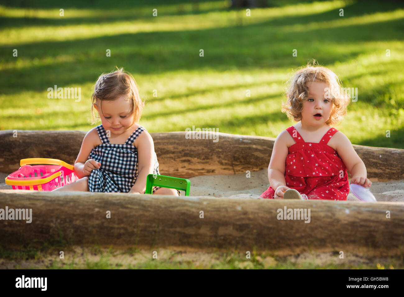 The two little baby girls playing toys in sand Stock Photo - Alamy