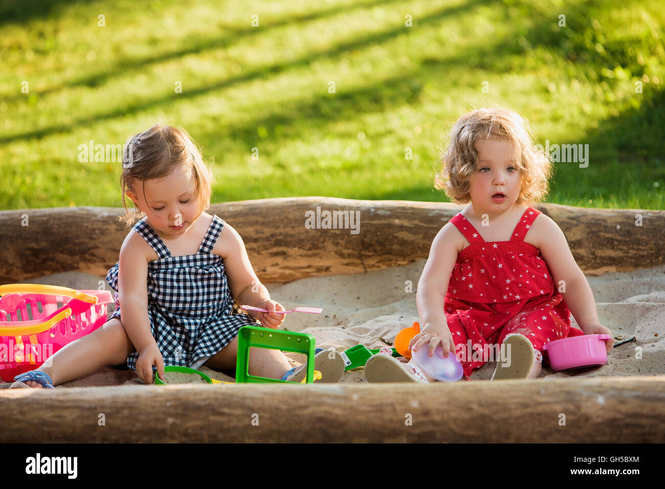 The two little baby girls playing toys in sand Stock Photo - Alamy