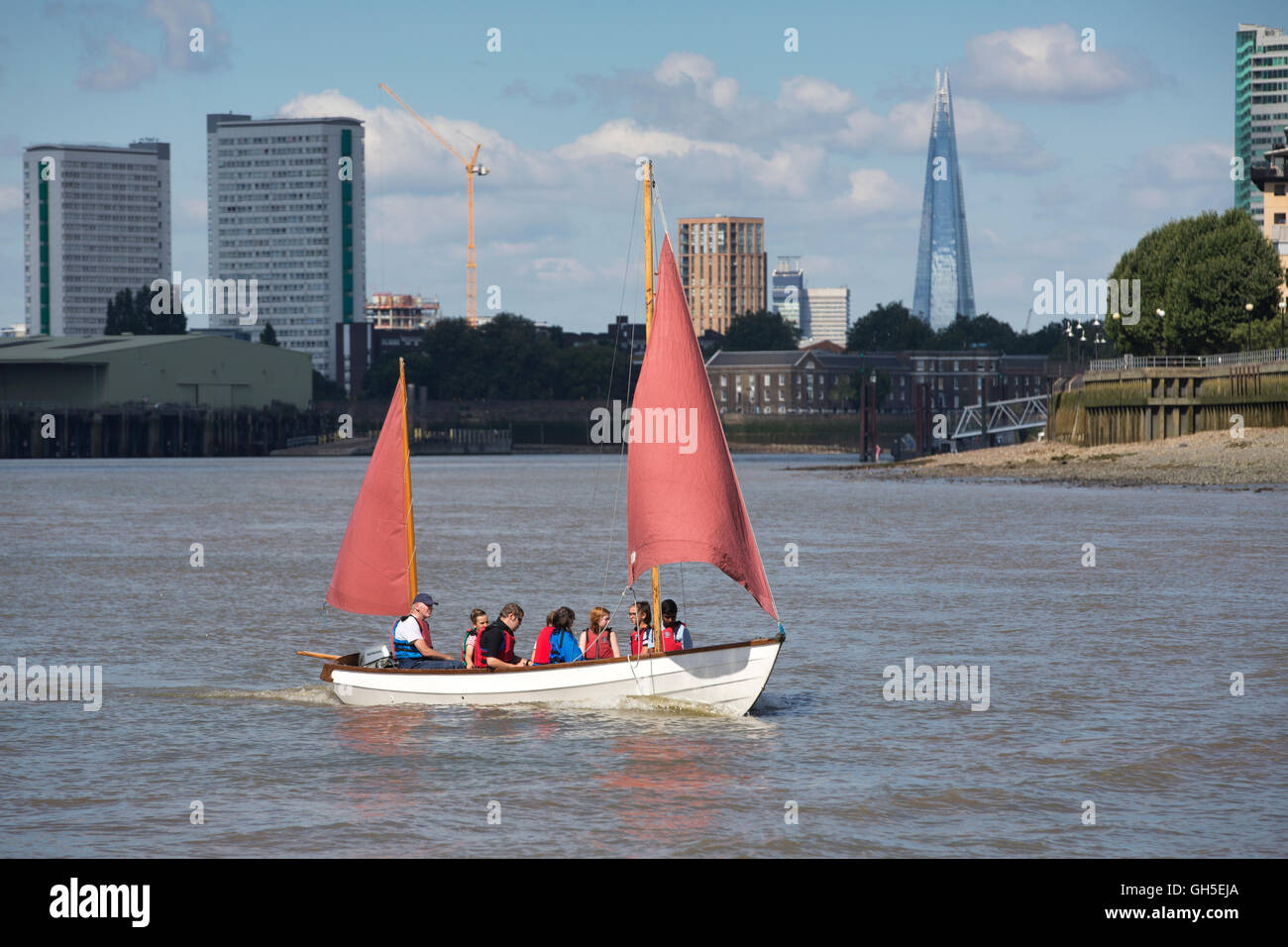 Group enjoying a sailing trip on a wooden dingy along the River Thames, the Shard skyscraper clearly visible in distance, London Stock Photo