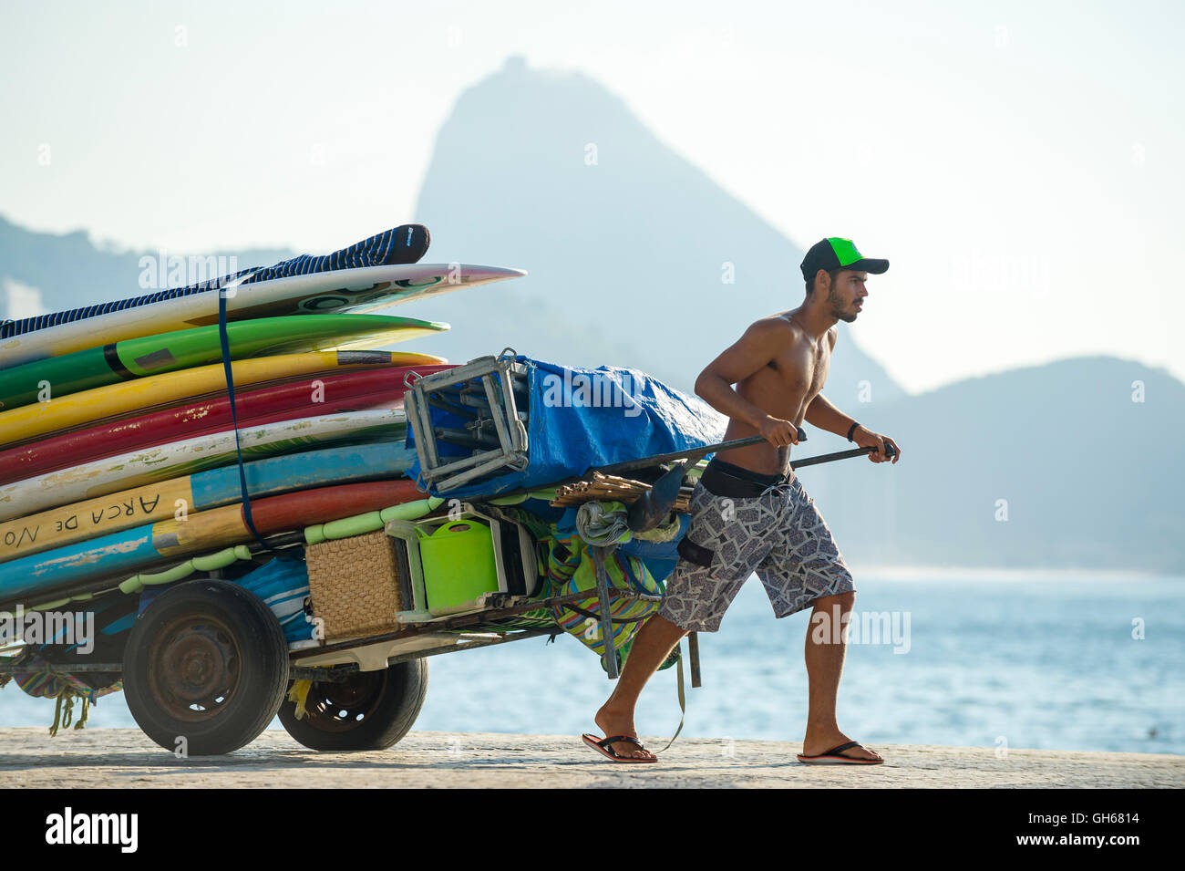 RIO DE JANEIRO - APRIL 5, 2016: Young carioca Brazilian man pulls a cart of stand up paddle SUP surfboards. Stock Photo