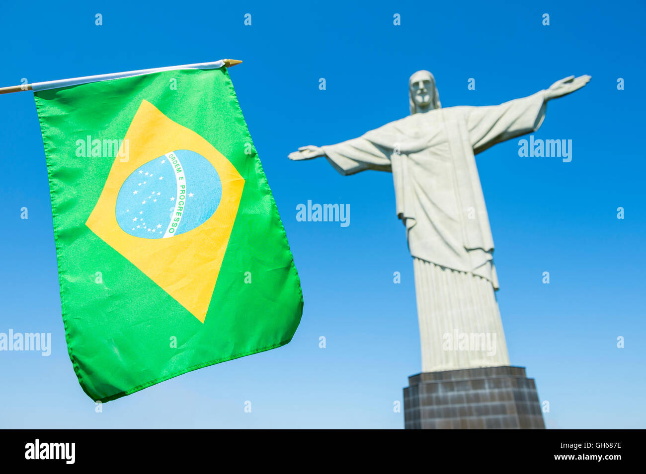 RIO DE JANEIRO - MARCH 21, 2016: Brazilian flag waves in front of statue of Christ the Redeemer at Corcovado. Stock Photo