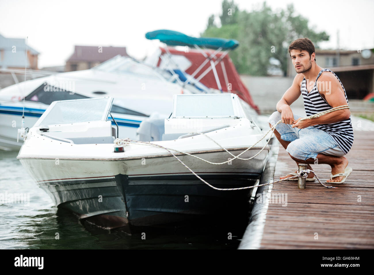 Young handsome man preparing boat to start a journe at the pier Stock Photo