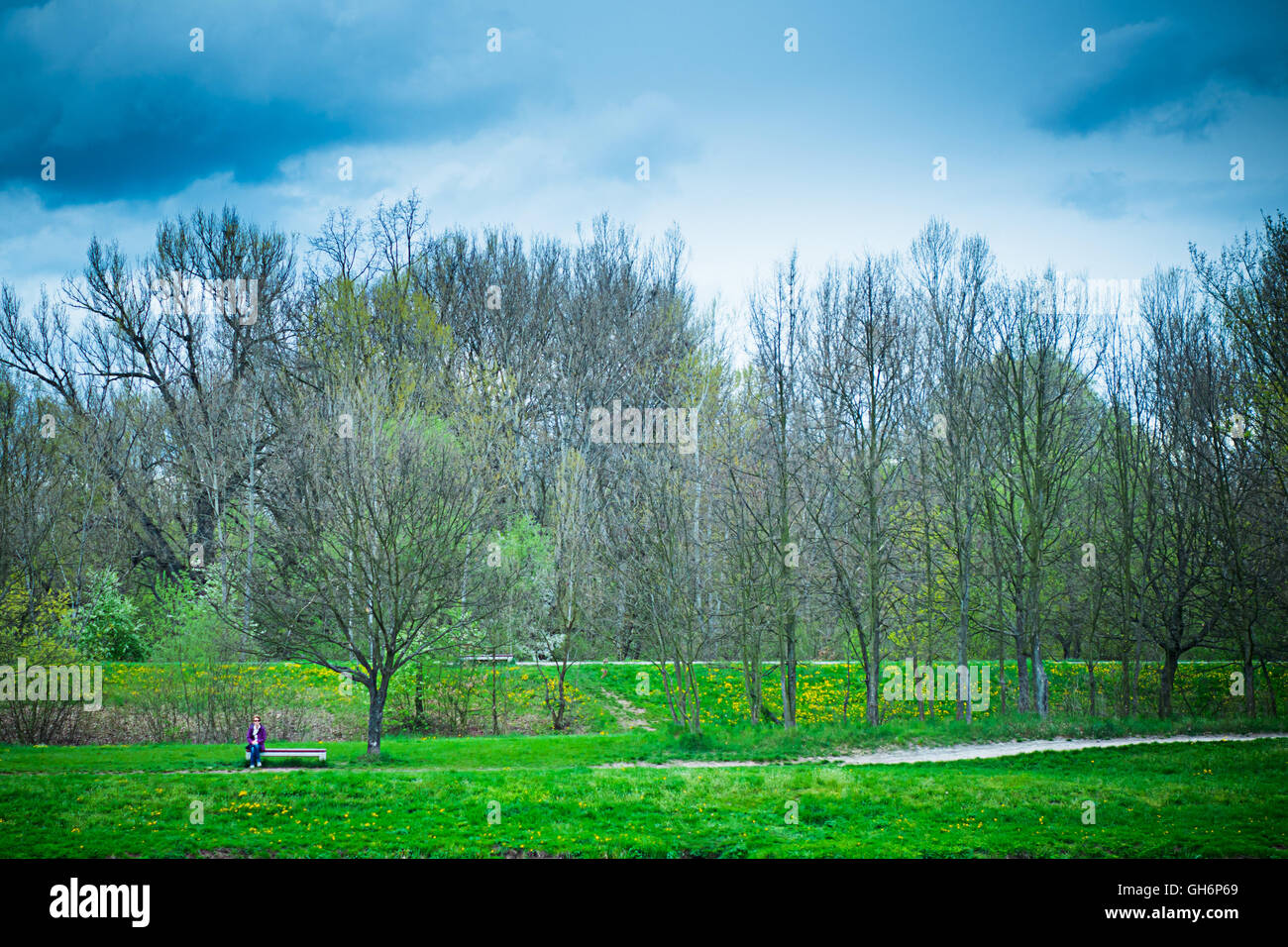 lonely woman sitting on a bench in nature Stock Photo