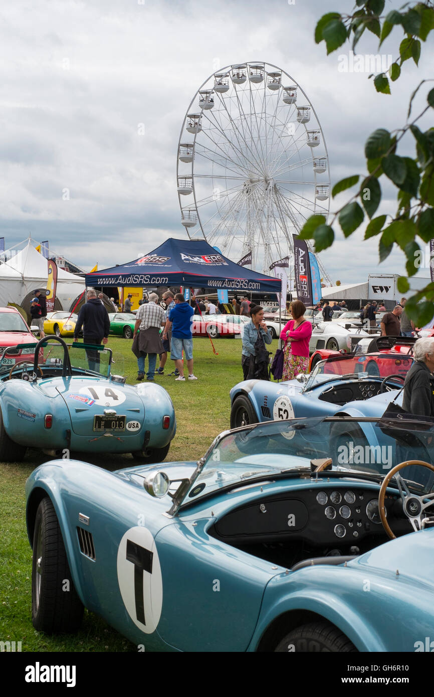 AC Cobra sports cars and a big wheel at the 2016 Silverstone Classic event. Stock Photo