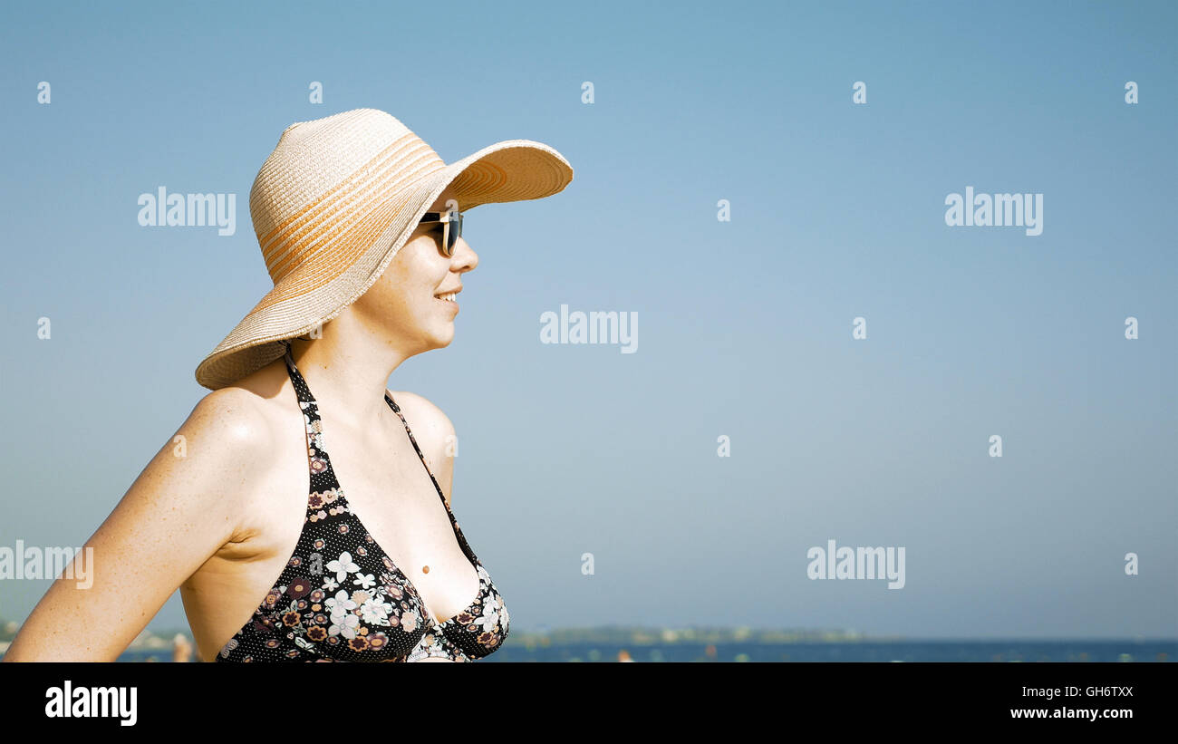Woman standing on the beach with her fancy hat Stock Photo
