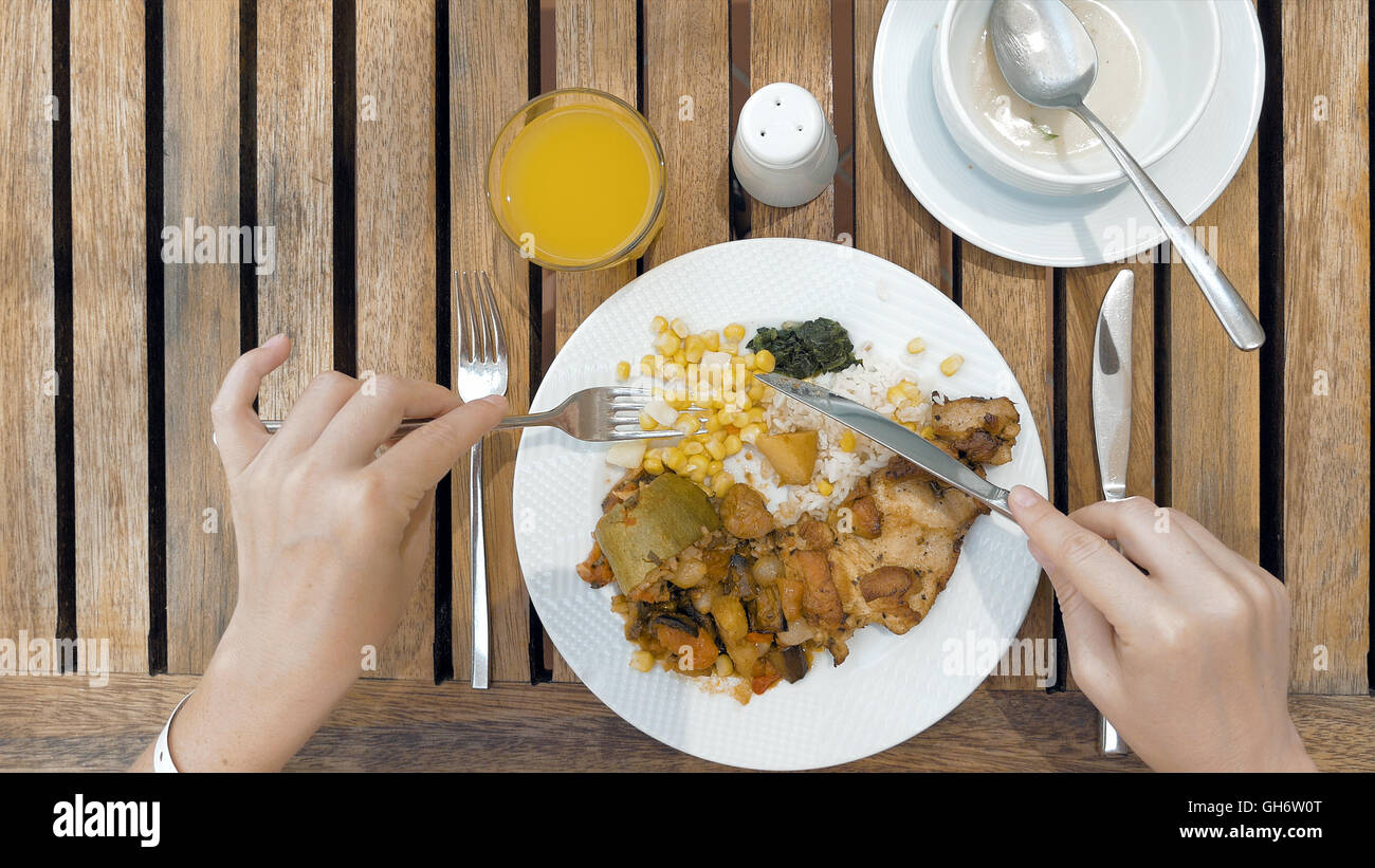 Lady is using utensils to cut meal in small bites Stock Photo