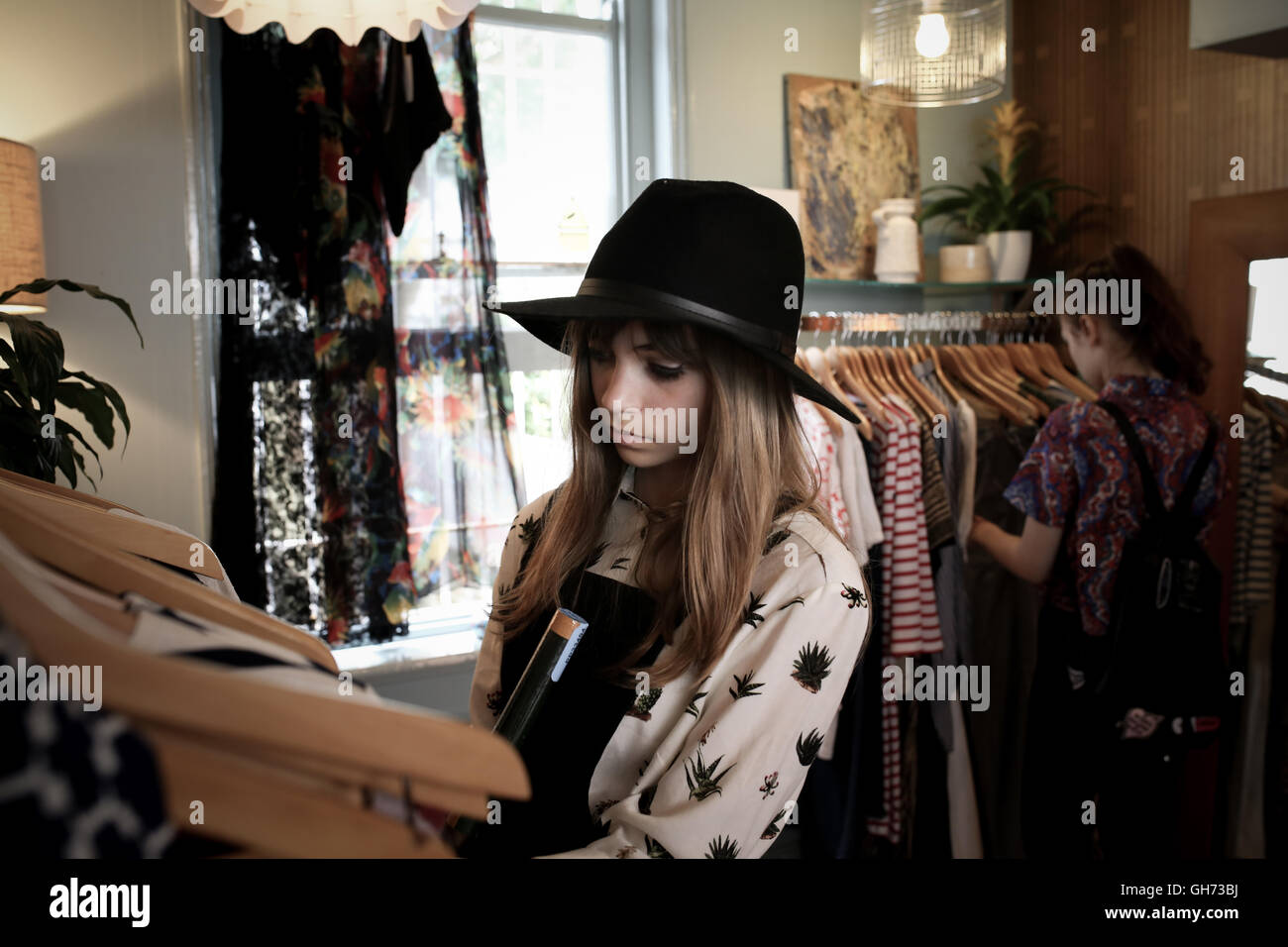 Two teenage girls in a vintage clothes store browsing the clothes Stock Photo