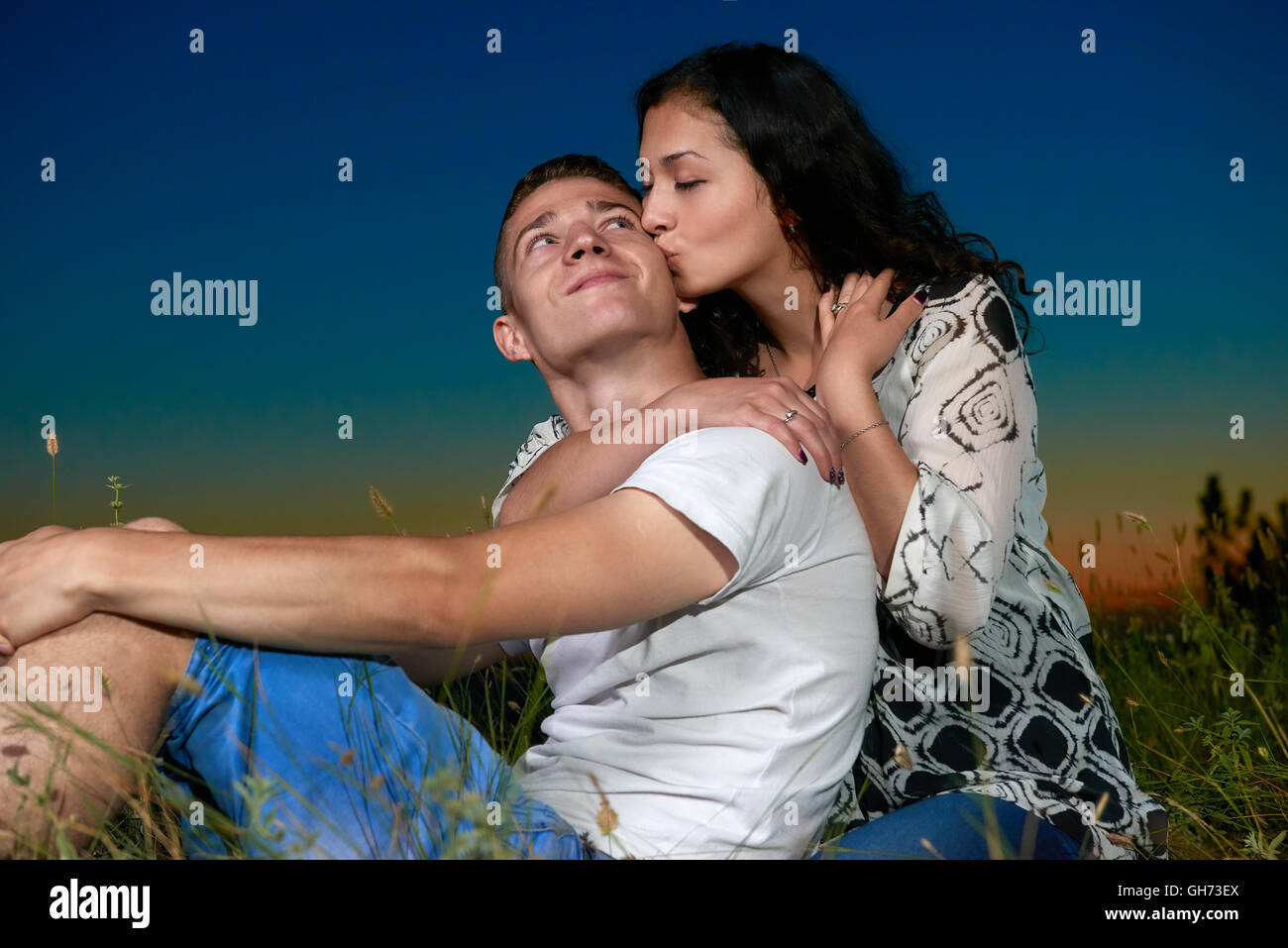 romantic couple kiss on grass and ebmbrace on country outdoor, dark night sky, love concept, young adult people Stock Photo