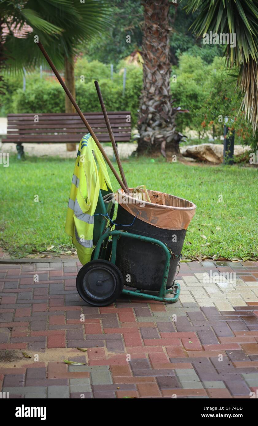 Mobile Waste Can. Mobile waste can Mobile garbage can in a garden. Mobile trash can of a street cleaner with orange garbage bag containing a broom and Stock Photo