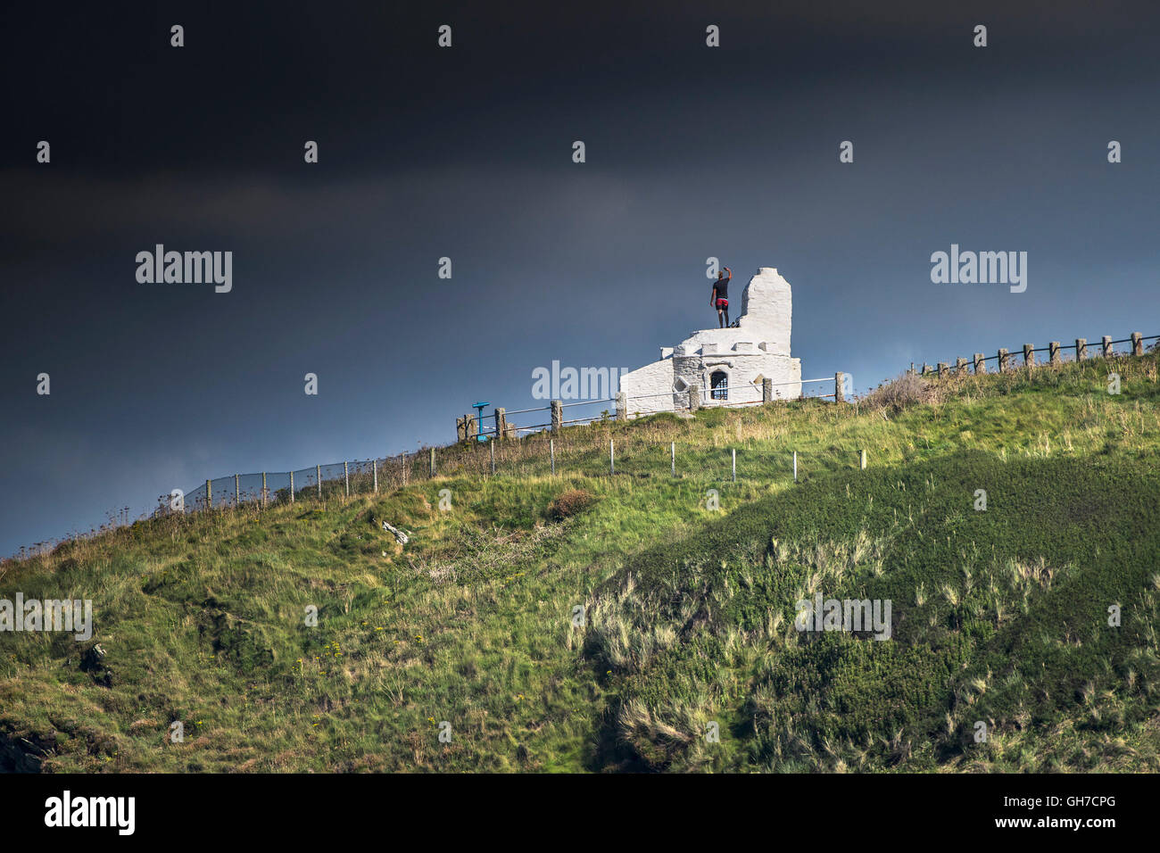 A tourist stands on the roof of the historic Huer’s Hut in Newquay, Cornwall. Stock Photo