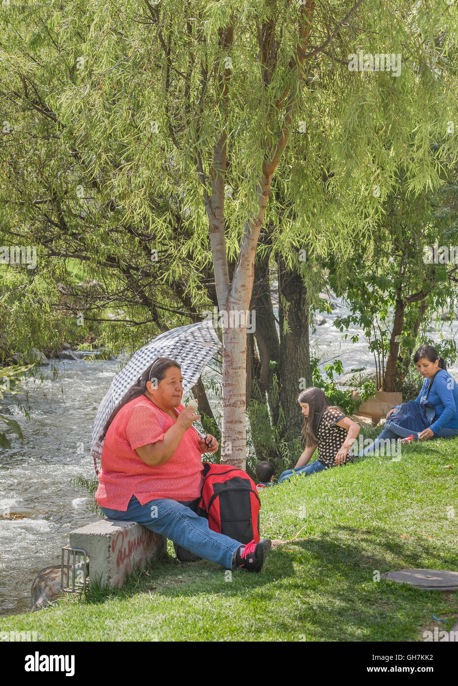 CUENCA, ECUADOR, NOVEMBER - 2015 - Group of people enjoying the day at park in front of river in Cuenca, Ecuador Stock Photo