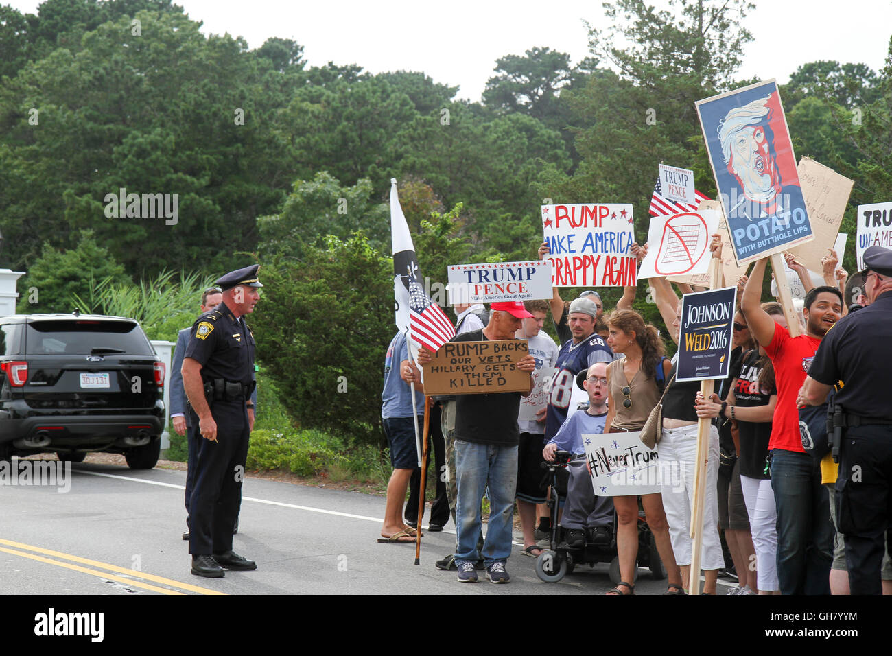 Osterville, Massachusetts, USA. 6th August, 2016. Protesters hold signs opposing Republican presidential nominee Donald Trump, near a fundraiser businessman William Koch is hosting for Trump. A pro-Trump counter-protester standing to the left also holds signs. Credit:  Susan Pease/Alamy Live News Stock Photo