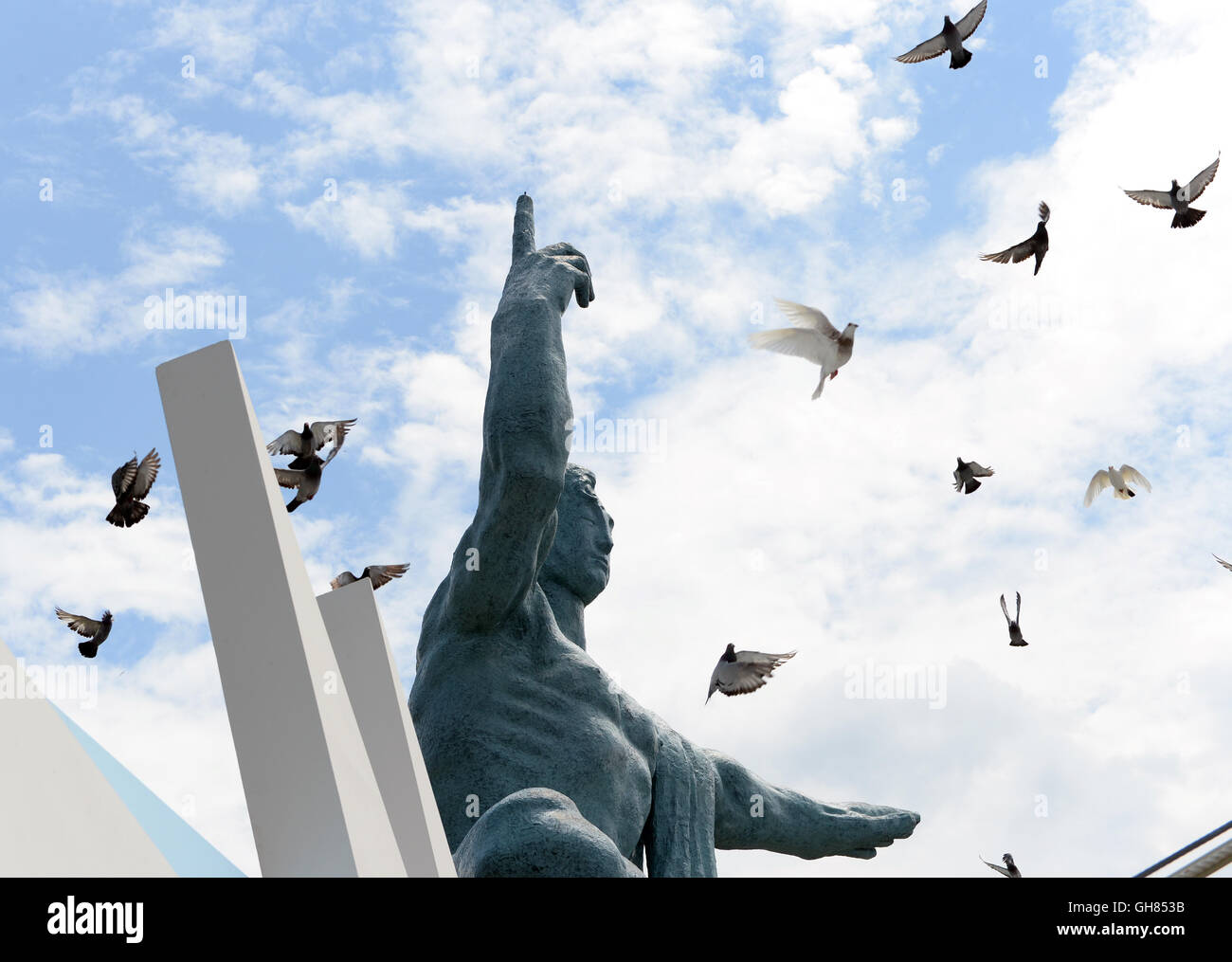 Nagasaki. 9th Aug, 2016. Pigeons fly around the Peace Statue at the Peace Park in Nagasaki, on Aug. 9, 2016, the 71st anniversary of U.S. atomic bombing. To accelerate Japan's surrender in the World War II, the U.S. forces dropped two atomic bombs on Hiroshima and Nagasaki respectively on Aug. 6 and 9, 1945. Credit:  Ma Ping/Xinhua/Alamy Live News Stock Photo