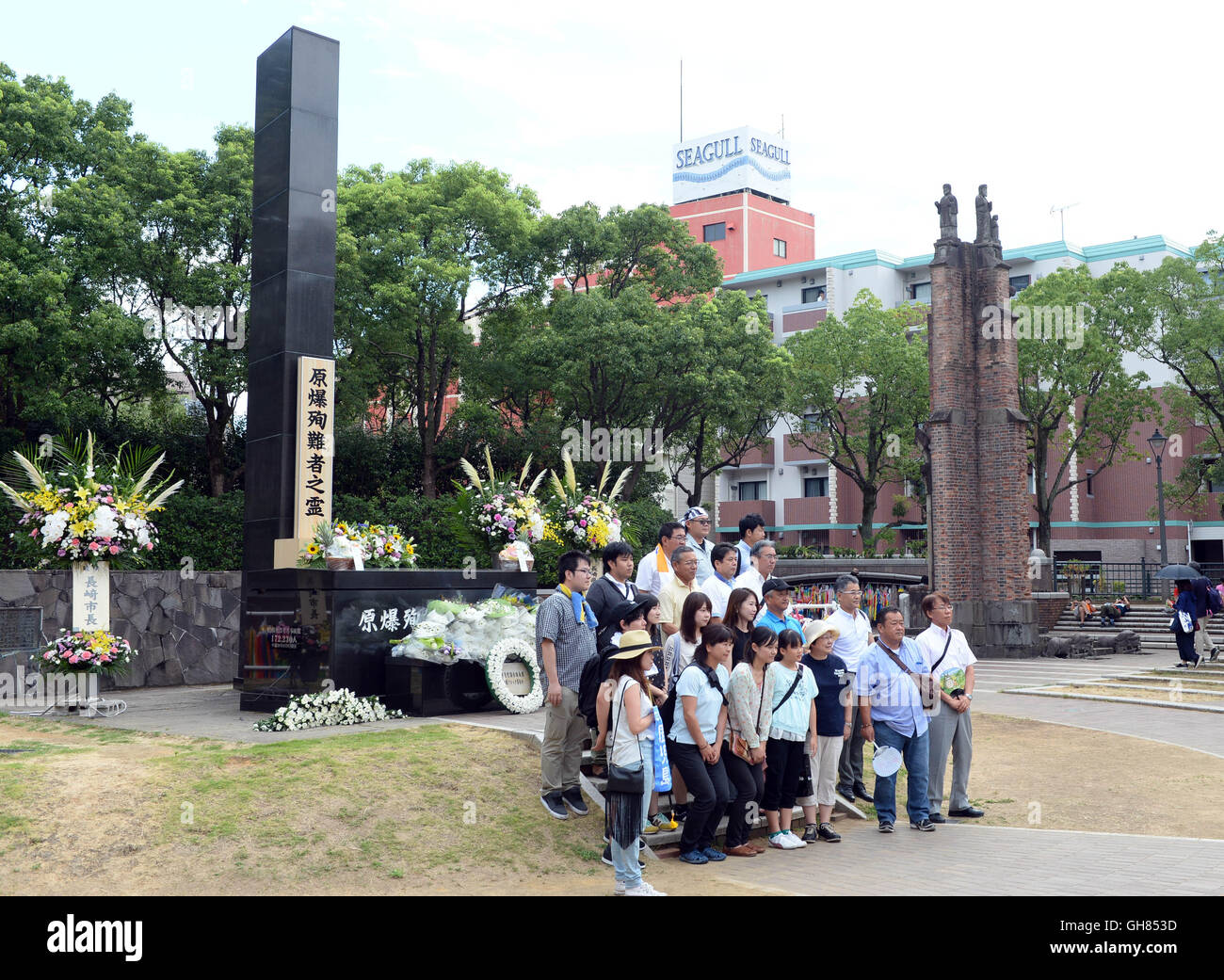 Nagasaki, Peace Park in Nagasaki. 9th Aug, 2016. People pose for photos in front of the monument at the atomic bomb hypocenter to commemorate the 71st anniversary of U.S. atomic bombing, at the Peace Park in Nagasaki, on Aug. 9, 2016. To accelerate Japan's surrender in the World War II, the U.S. forces dropped two atomic bombs on Hiroshima and Nagasaki respectively on Aug. 6 and 9, 1945. Credit:  Ma Ping/Xinhua/Alamy Live News Stock Photo