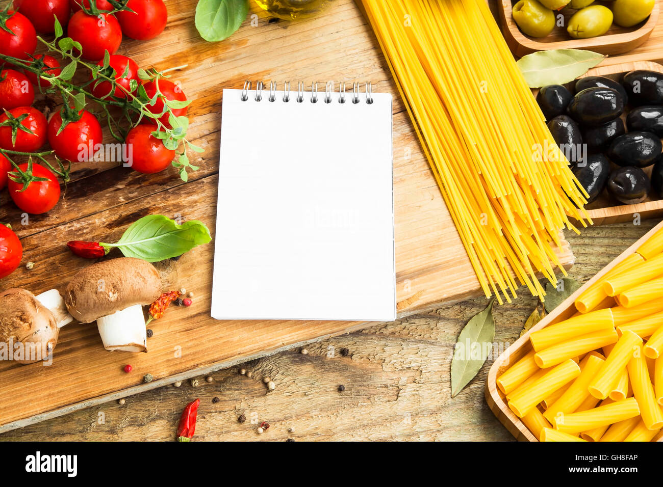 Italian spaghetti pasta with ingredients and recipe notebook .Basil