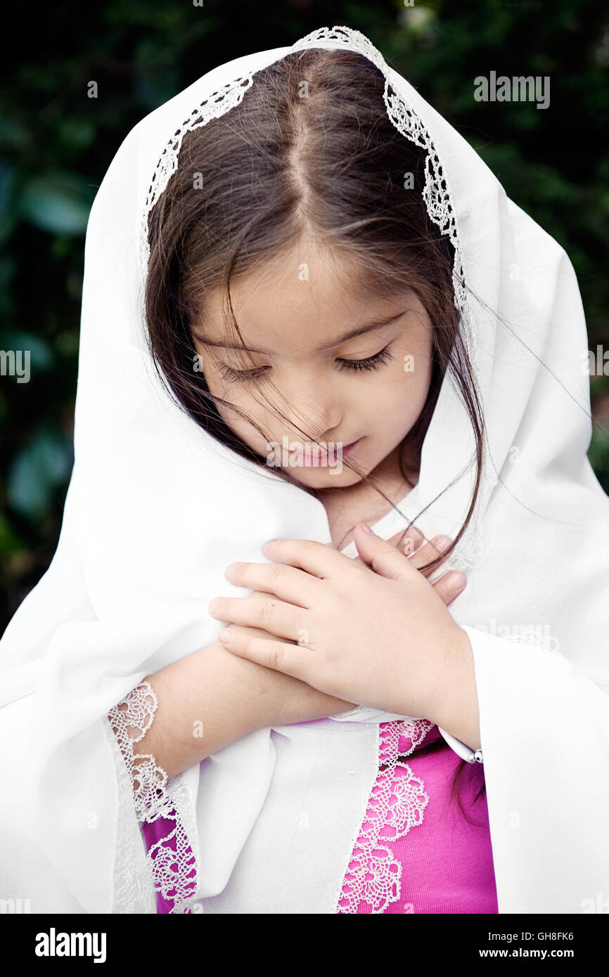 Little girl with headscarf looking down,hands on chest Stock Photo Alamy