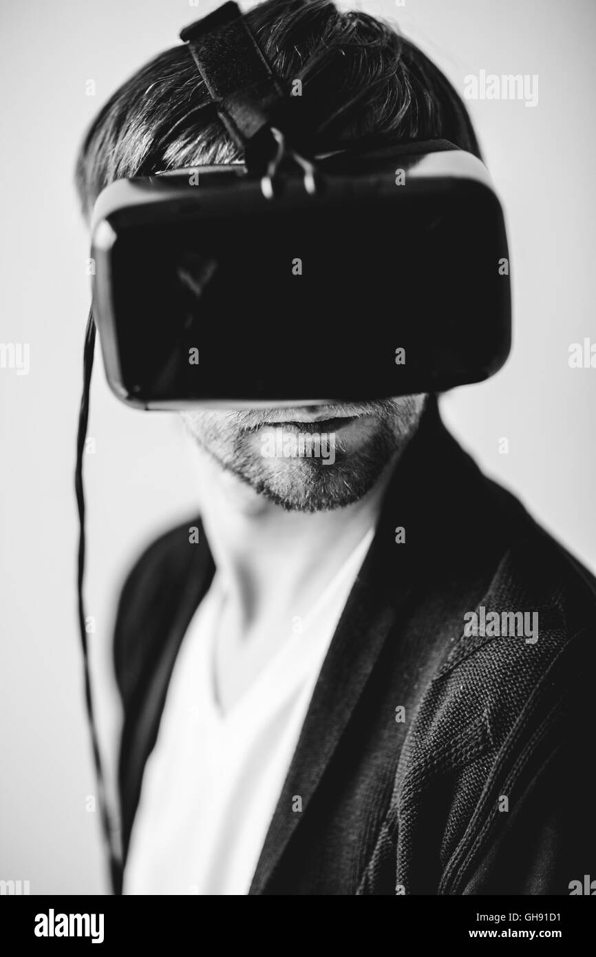 Handsome man wearing virtual reality glasses isolated on a gray background Stock Photo