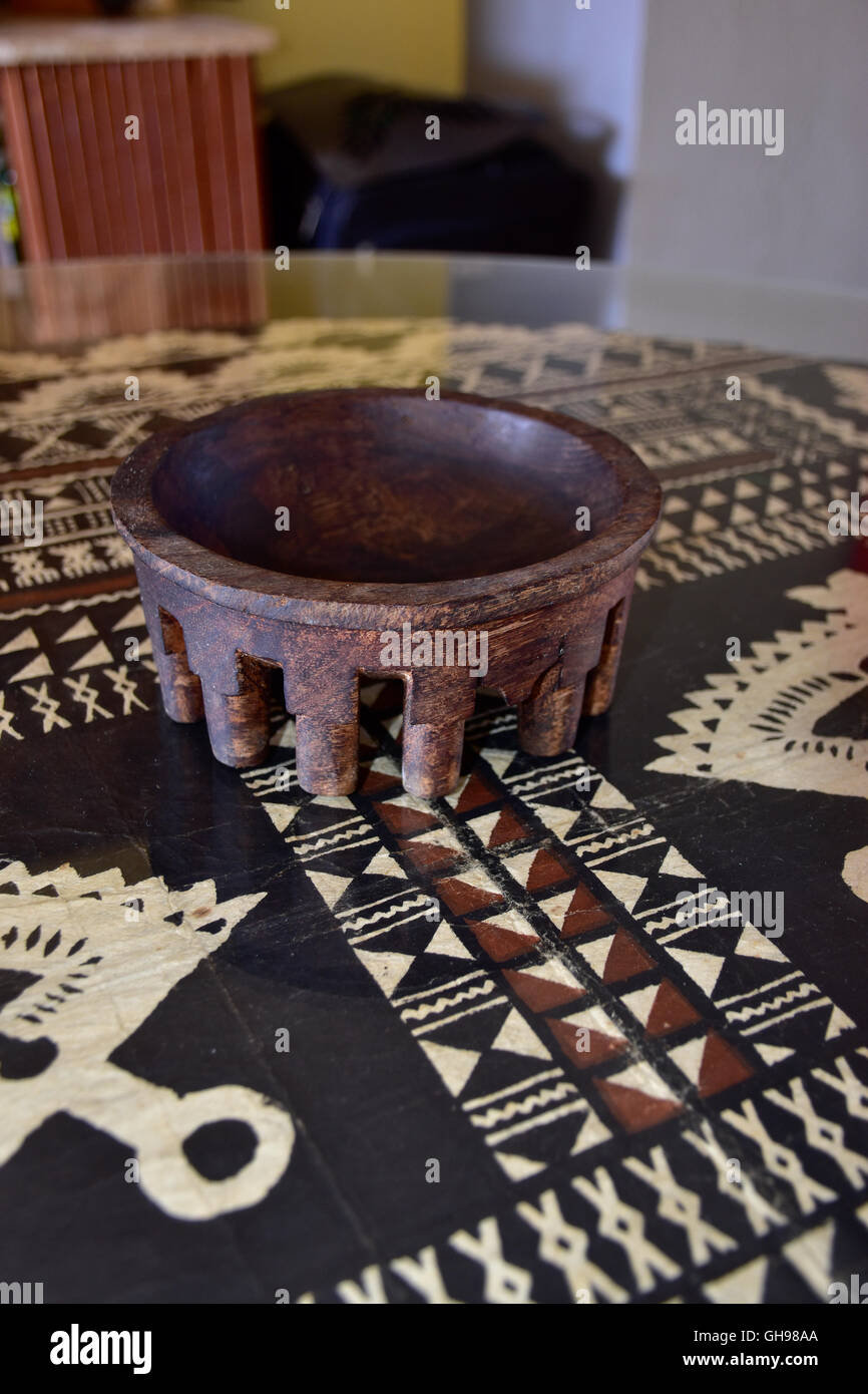 Antique Samoan tanoa or laulau kava bowl carved out of wood. Samoan Tapa cloth under glass on table. Stock Photo