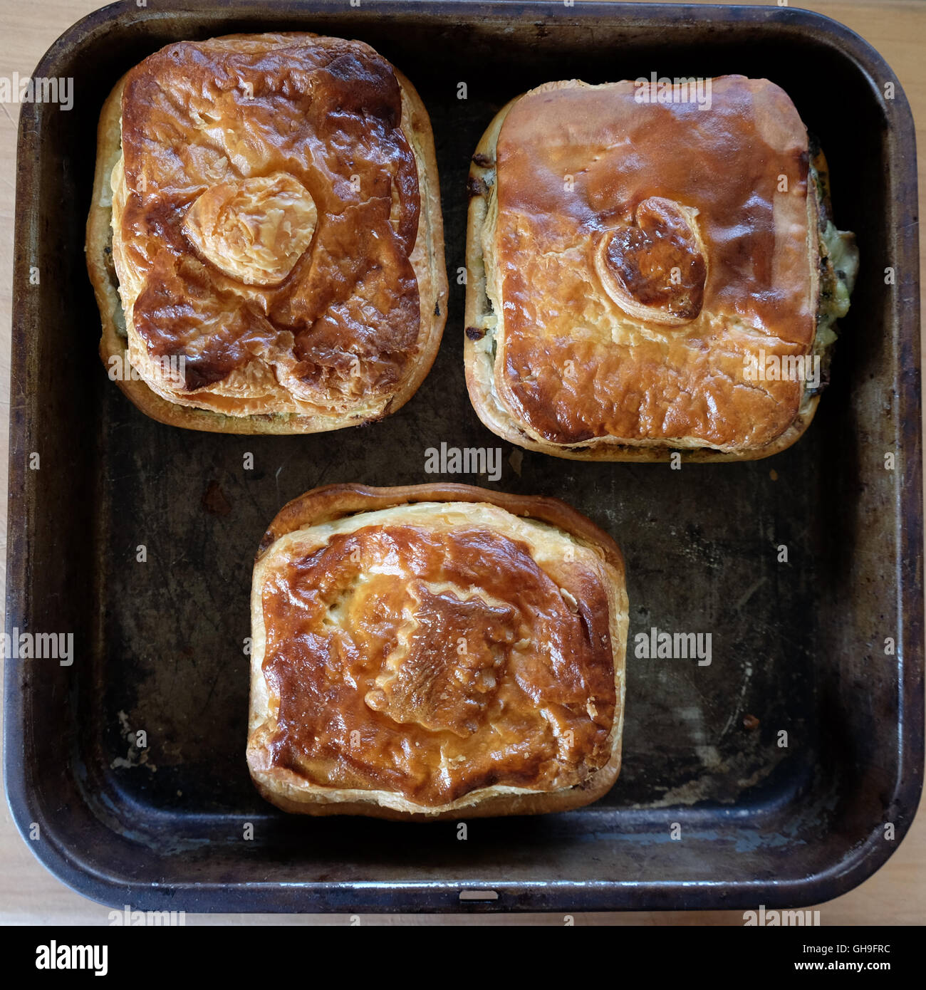 Savoury meat or vegetable pies on an old baking tray. Photographed in New Zealand, NZ. Stock Photo