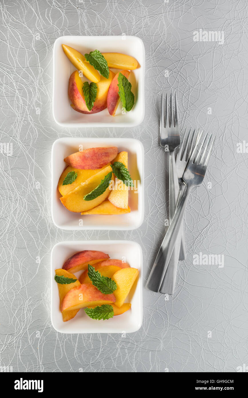 Raw peach slices served with mint Stock Photo