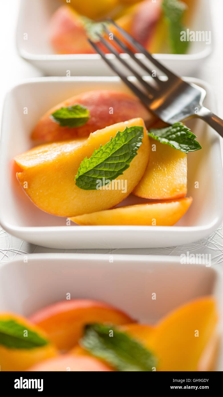 Raw peach slices served with mint Stock Photo