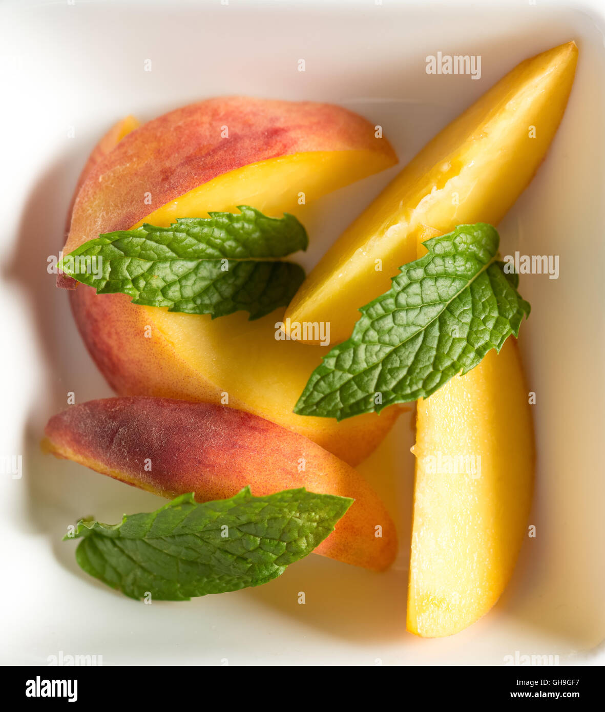 Raw peach slices served with mint Stock Photo