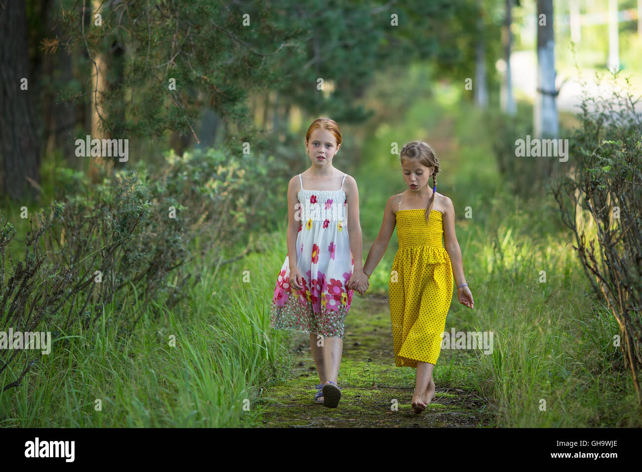 Two little girls walk through the Park holding hands Stock Photo - Alamy