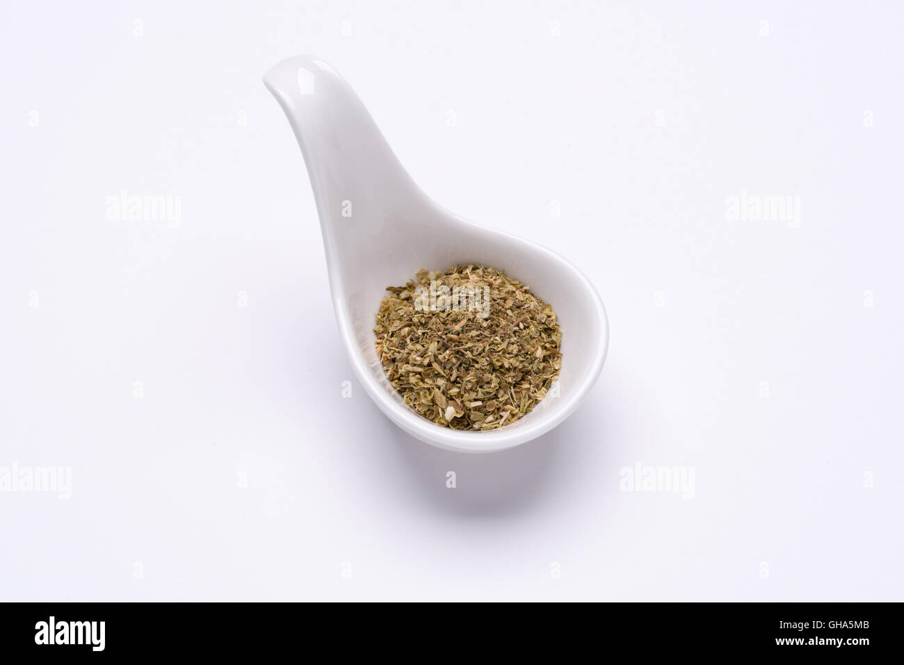 Monotone Oregano leaves 1 tablespoon in a white spoon on the white background Stock Photo