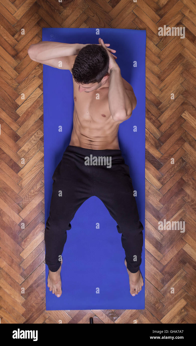 Young fit slim muscular sideway abs man exercise elevated view. laying mat Stock Photo