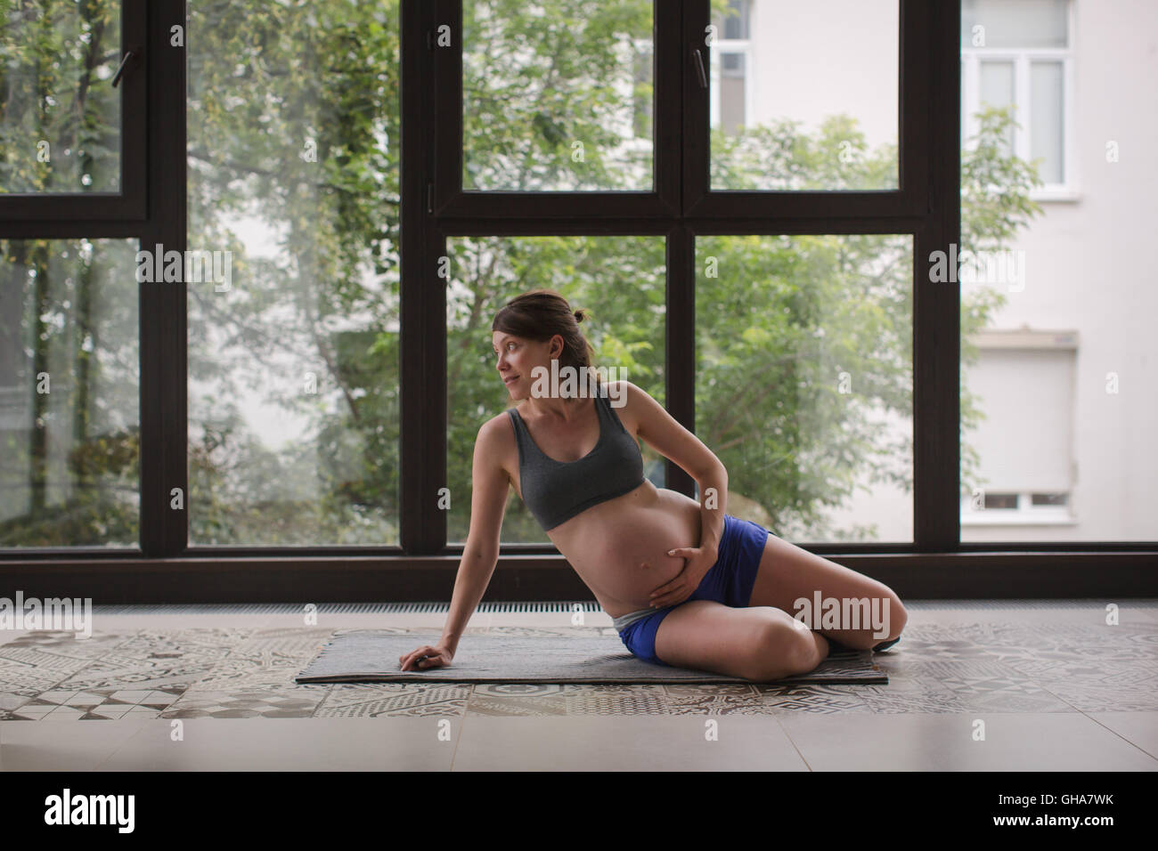 Pregnant woman on the mat before sports exercises Stock Photo