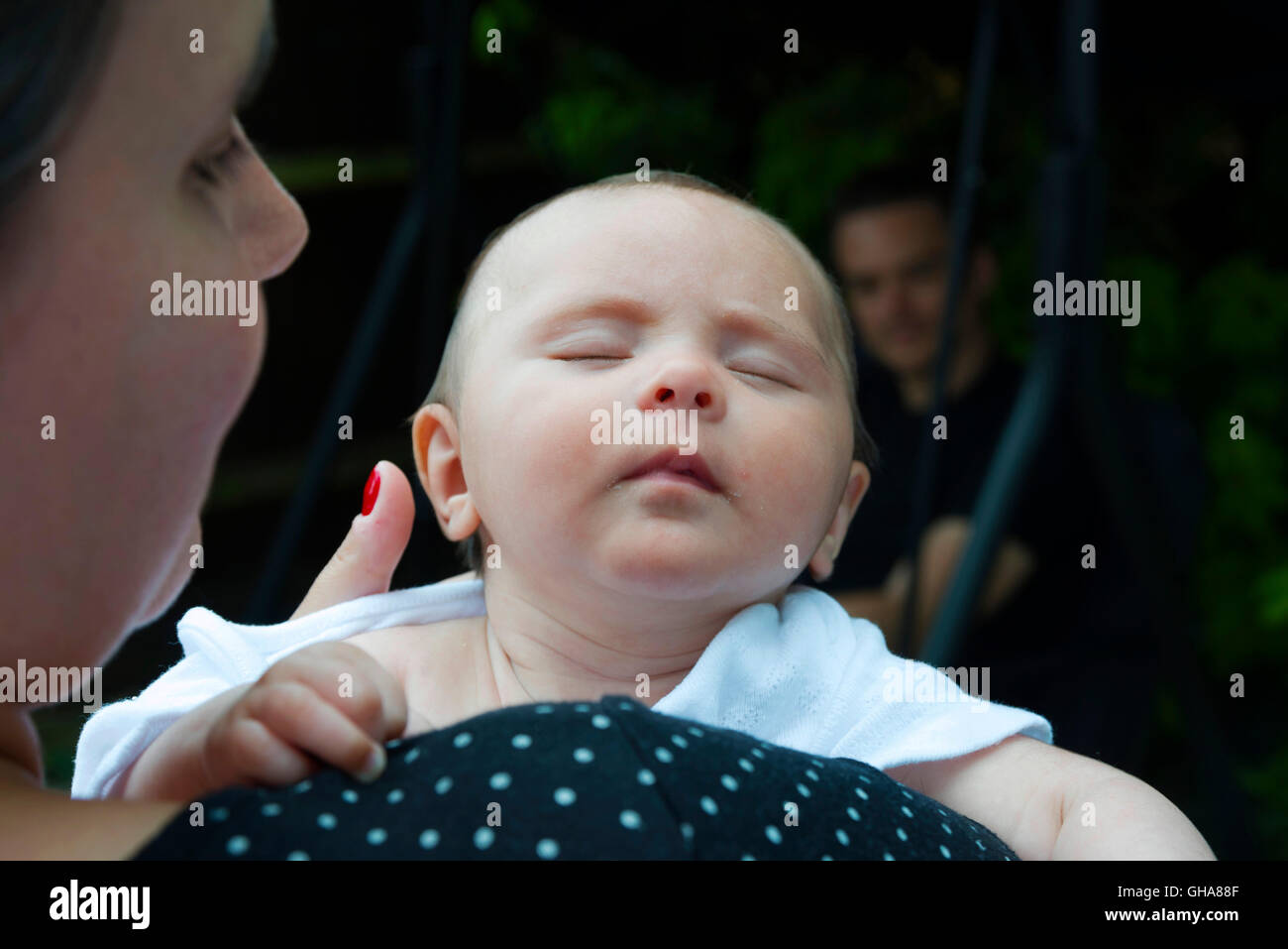 Upright sleeping newborn baby with mother and father Stock Photo