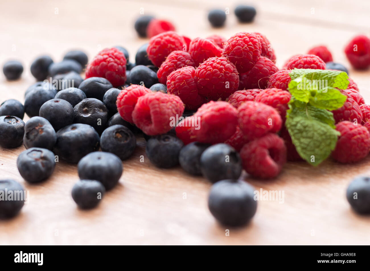 juicy raspberries and blueberries scattered on a wooden table Stock ...