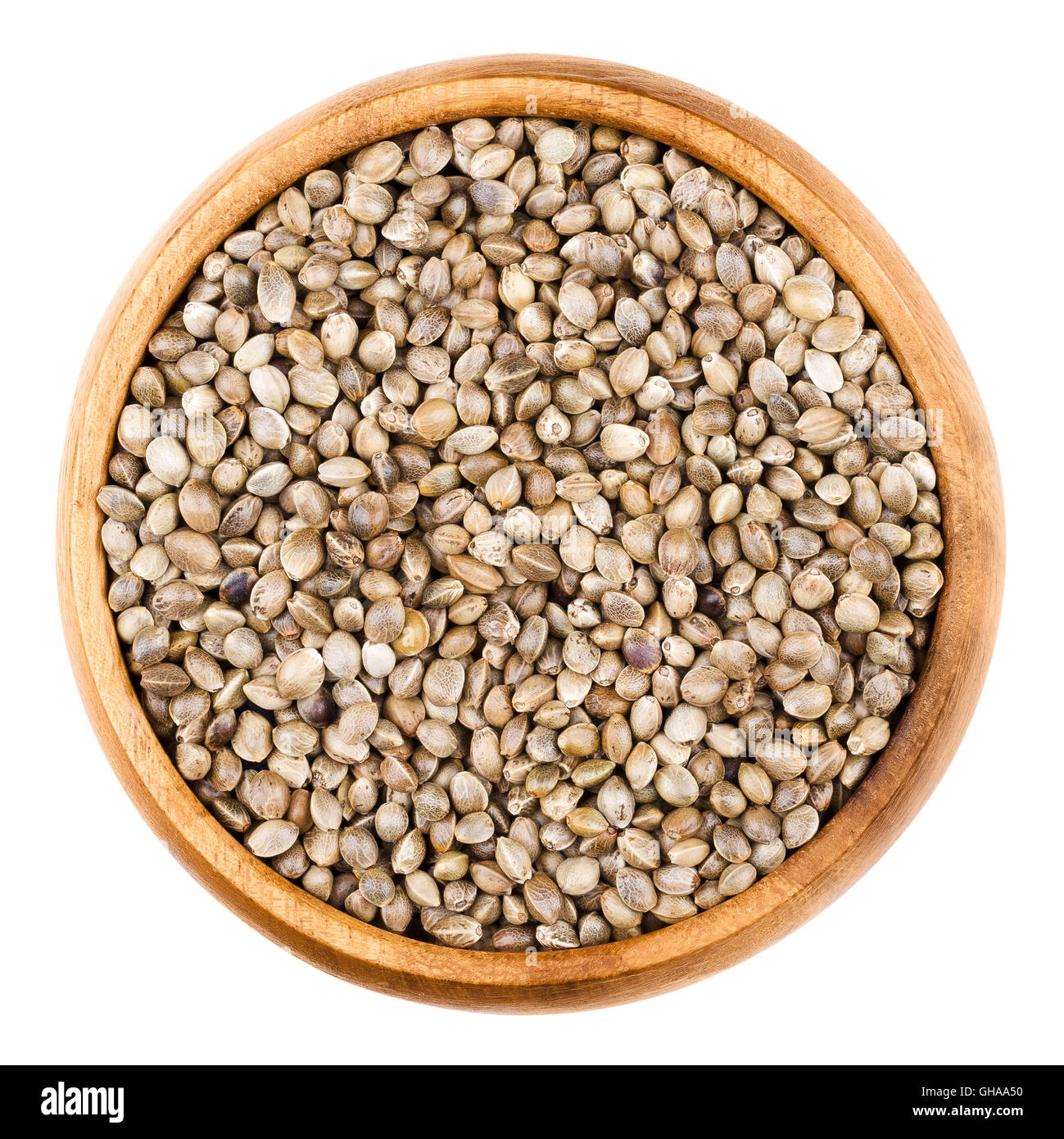 Hemp seeds in a wooden bowl on white background. Unshelled edible raw hempseeds of Cannabis sativa. Isolated close up macro. Stock Photo